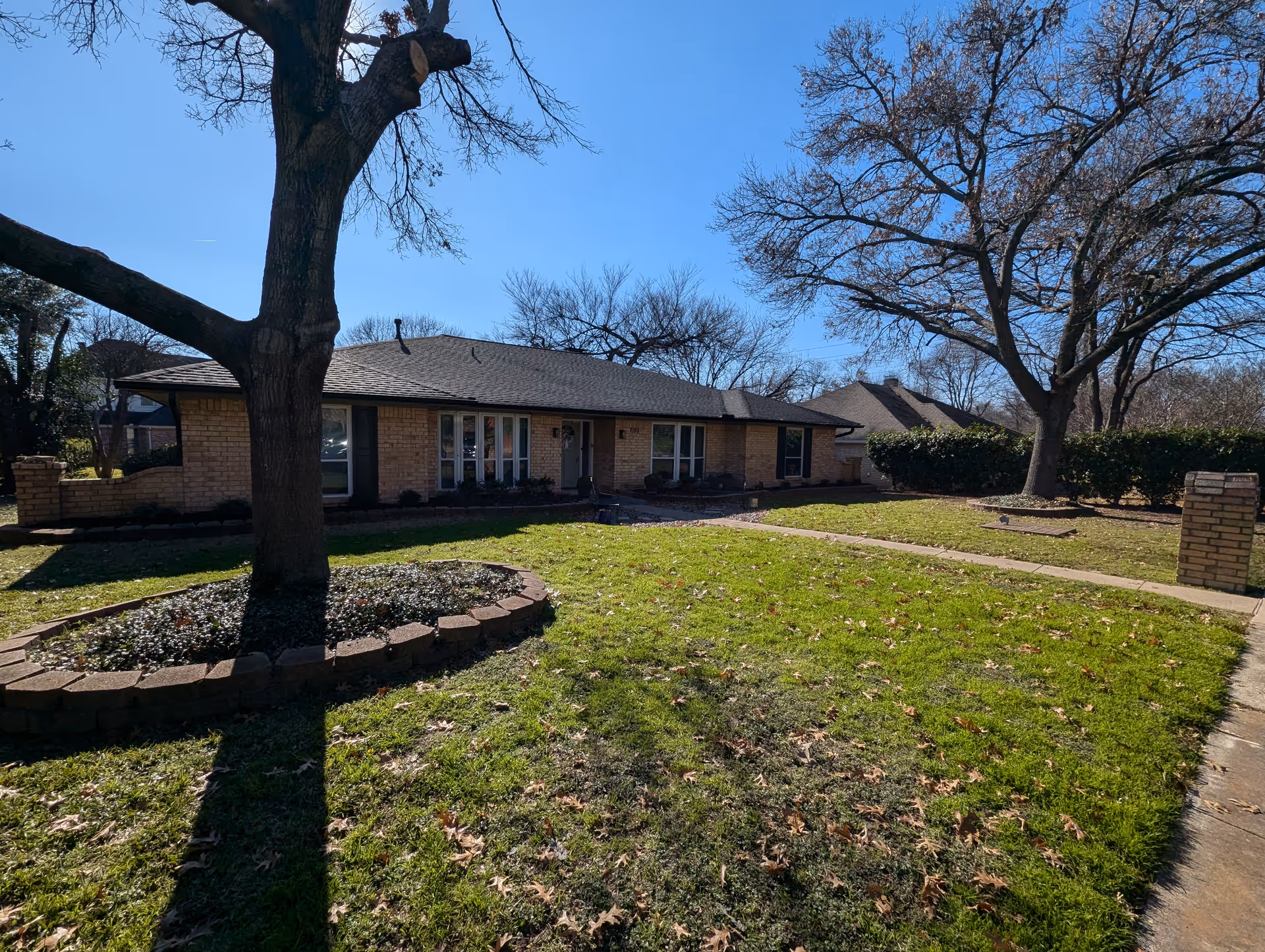 Single-story brick senior living facility with trees, lawn, and a walkway in front.