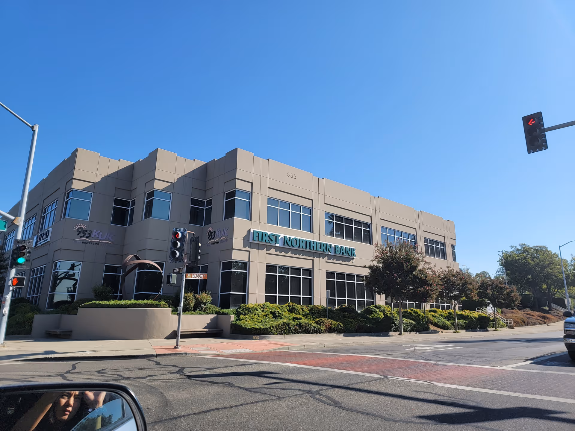Beige multi-story bank building with blue sign on a sunny street.