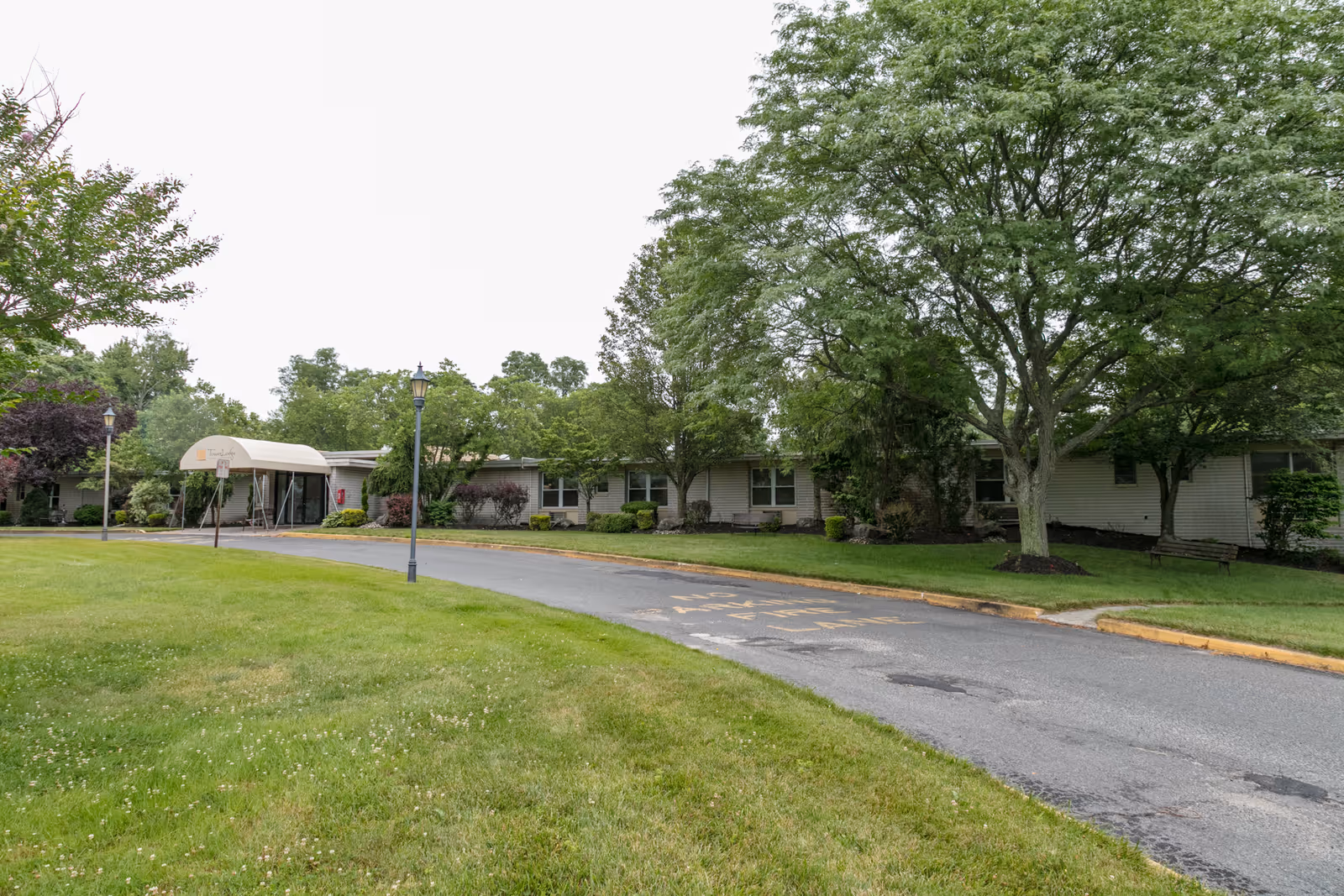 Exterior view of Tower Lodge Care Center with a driveway, trees, and a covered entrance.