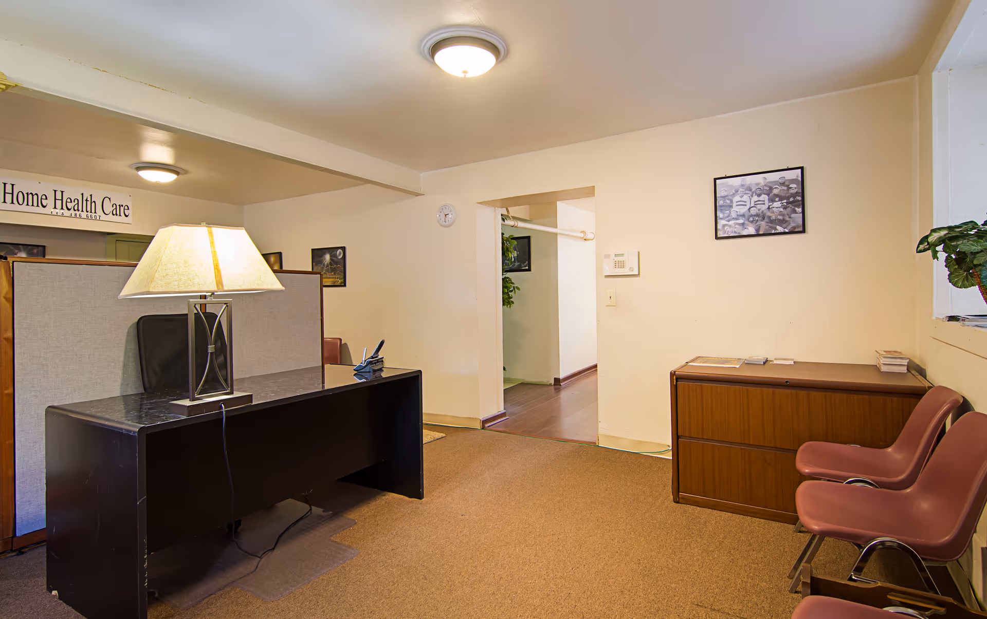 Reception area with desk, partition, chairs, lamp, and a Home Health Care sign.