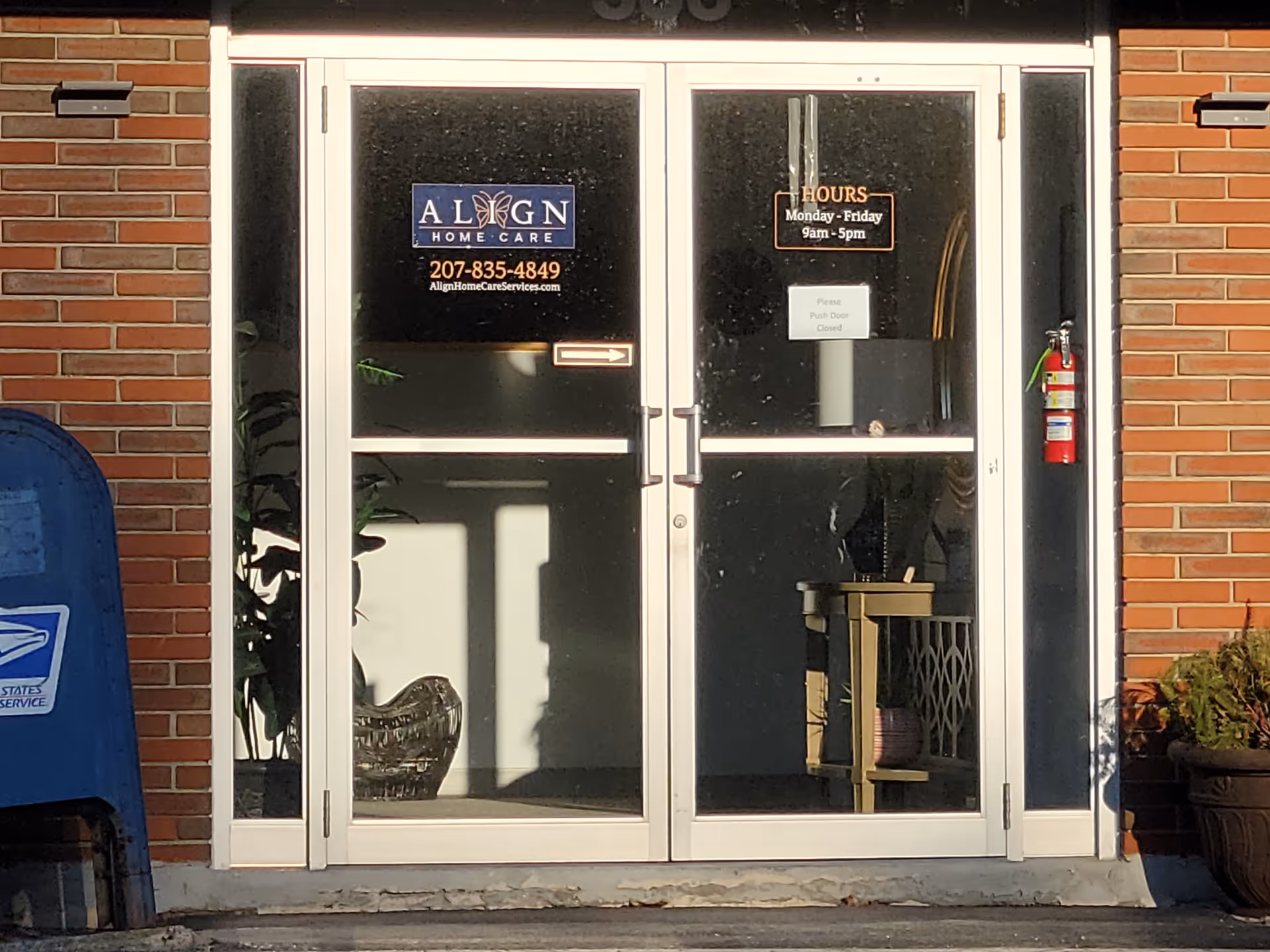 Glass double doors labeled Align Home Care, brick exterior, hours sign, plant and furnishings visible.