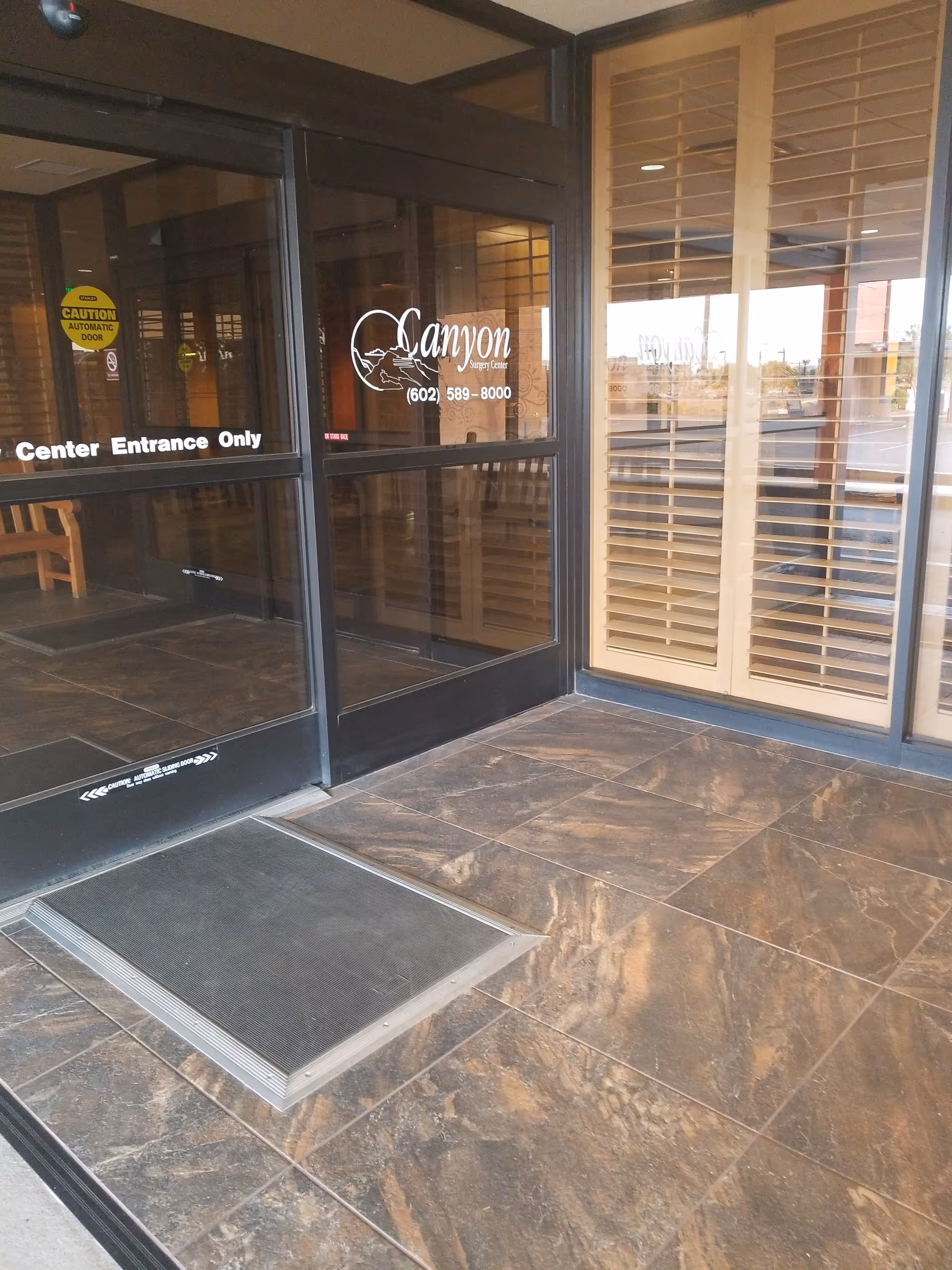 Glass entrance doors to Canyon Surgery Center, with tiled flooring and seating visible inside.