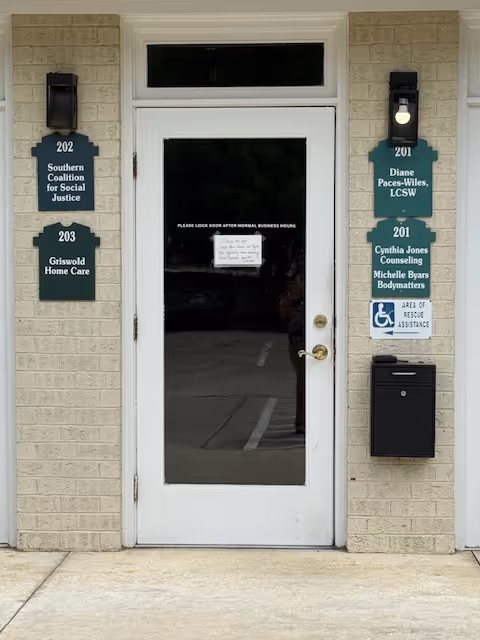 Facade of a senior care entrance with door, signs, and a mailbox on a brick wall