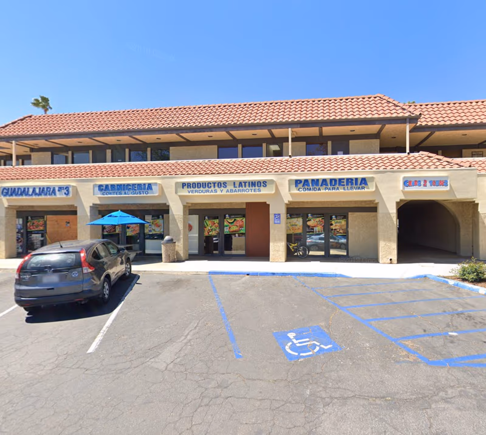 Exterior view of a strip mall with storefronts and a marked handicapped space.