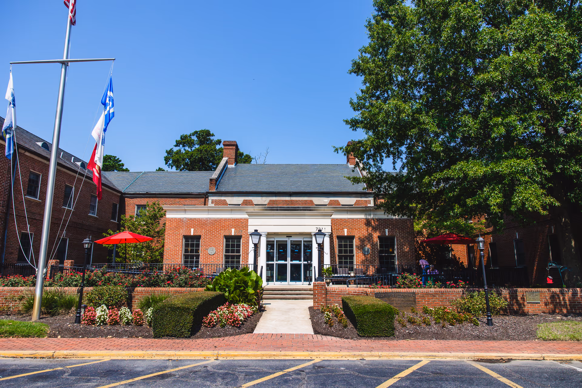 Brick building entrance of Commonwealth Senior Living at the Ballentine with flags and landscaping.