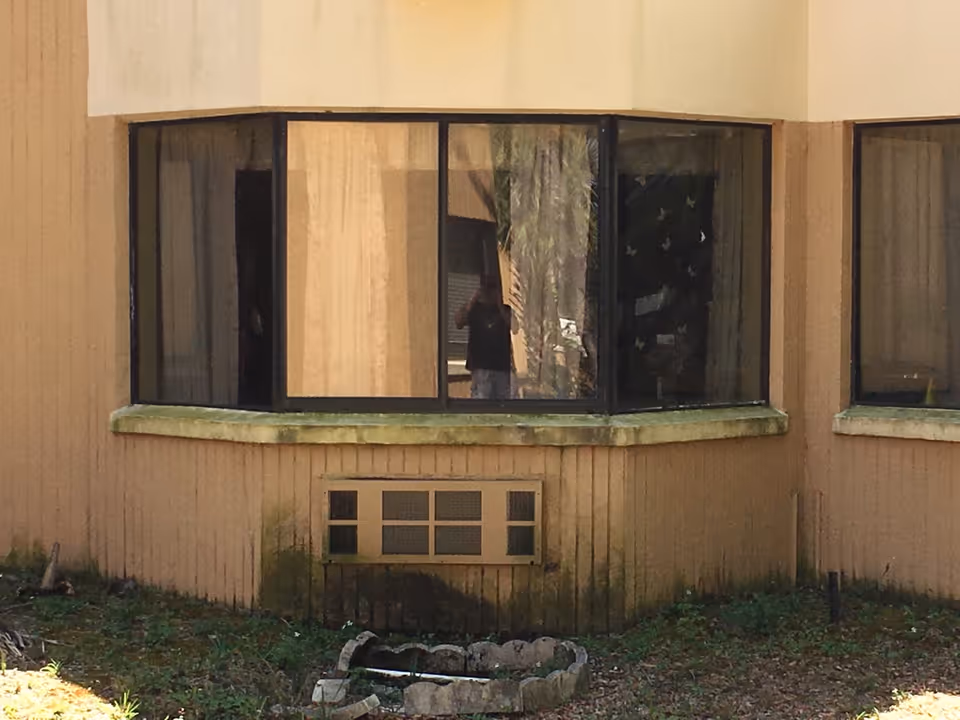 Beige exterior of a senior living building with a curved bay window and small vent.