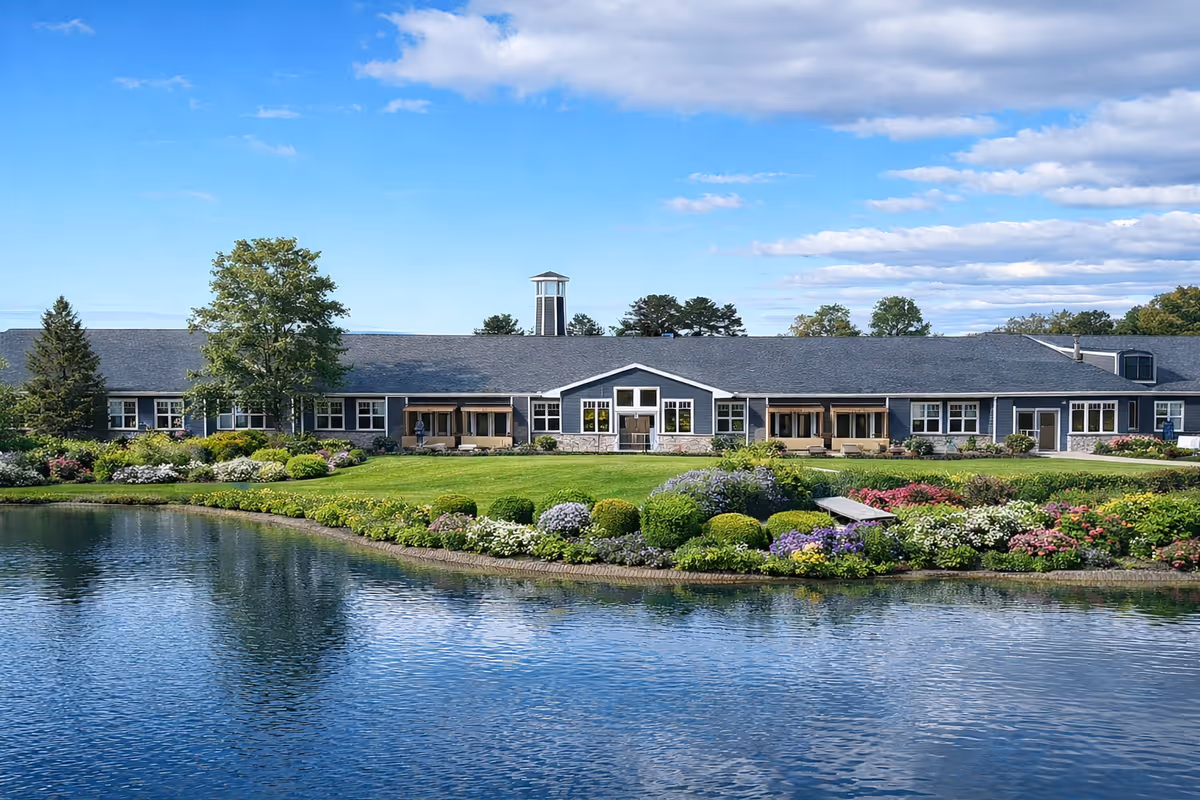 Single-story Bella Largo Senior Living building with manicured landscaping and a pond.