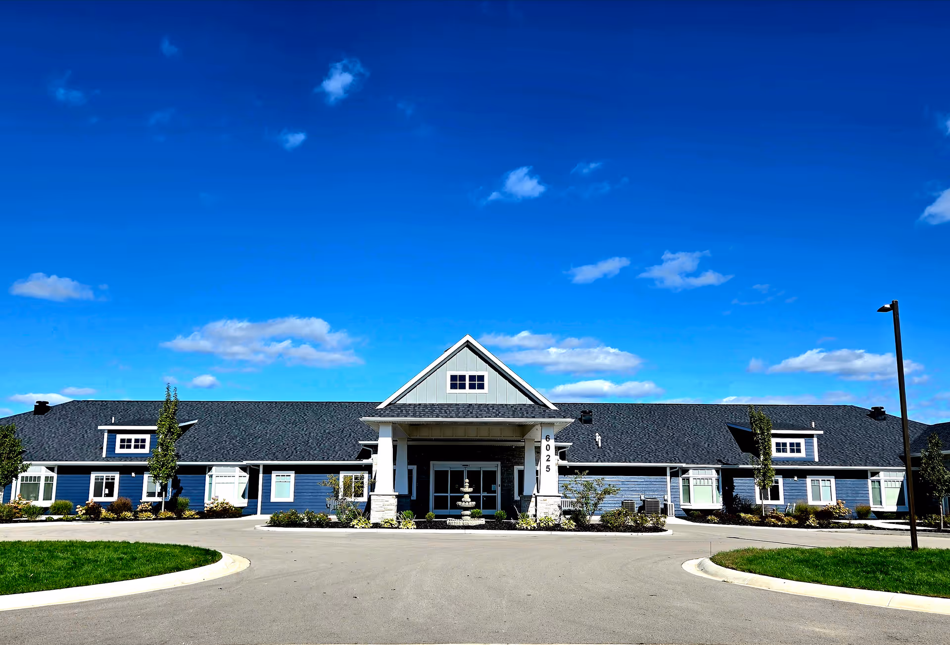 Blue, single-story senior living center with a peaked entrance and circular driveway