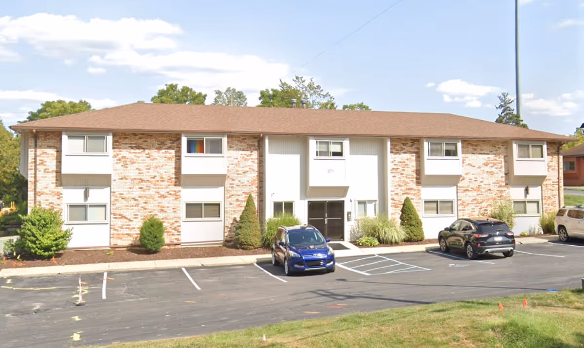 Exterior view of a brick two-story senior living building with parking.