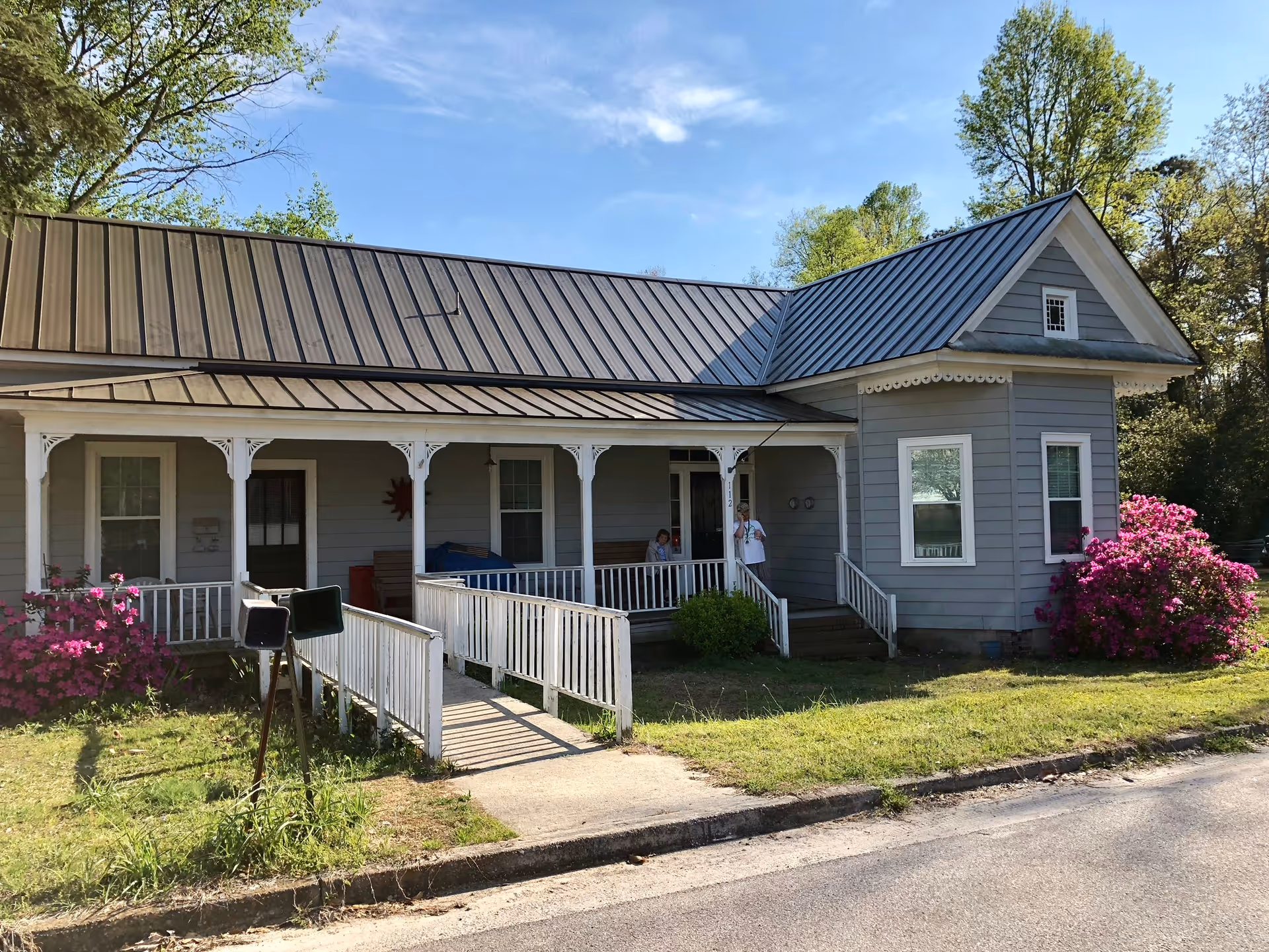 Front view of Village Inn Community Care Home with a blue-gray exterior, porch, and ramp.