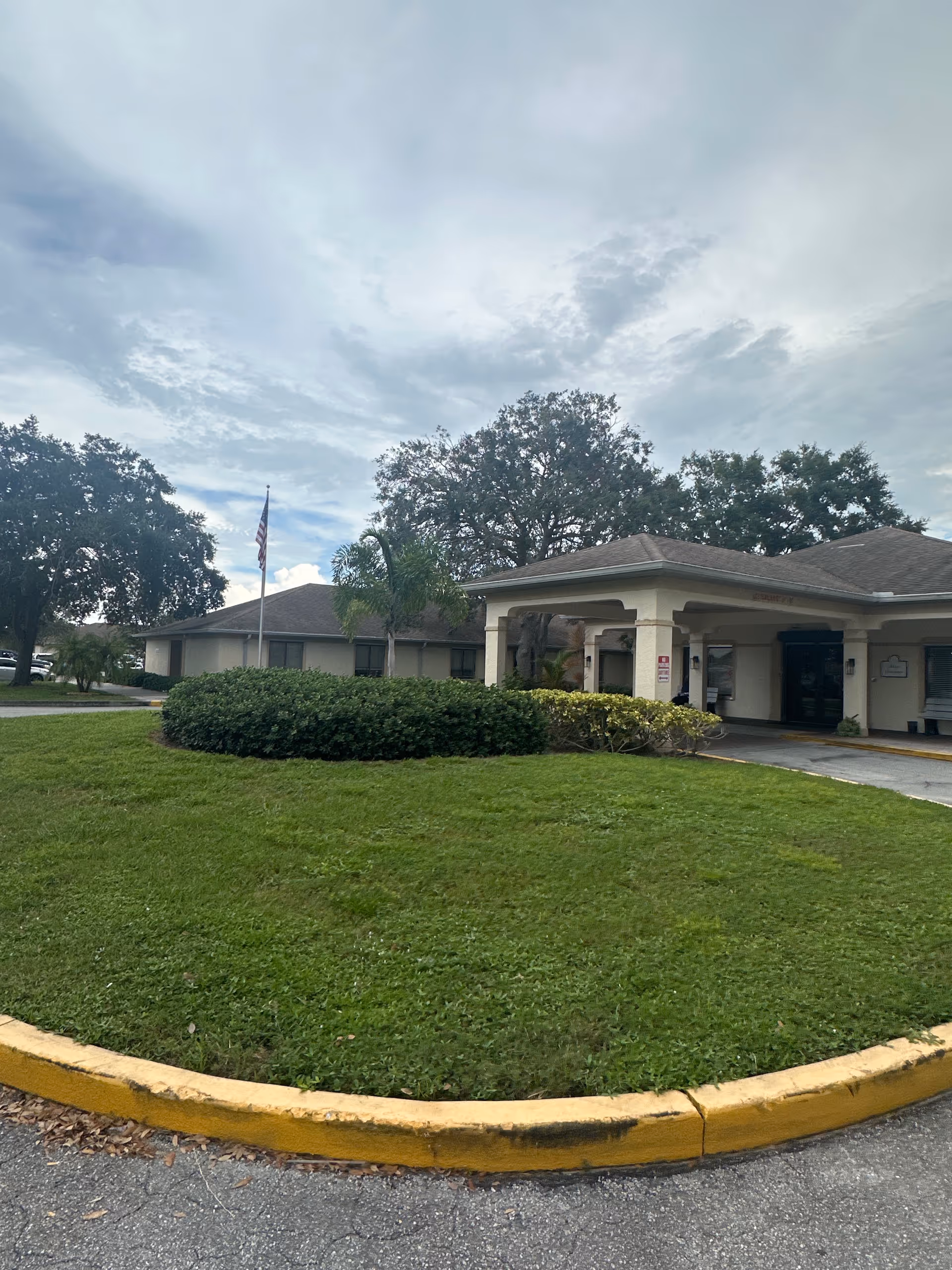 Front exterior view of a Nursing and Rehabilitation facility with a curved driveway and lawn.