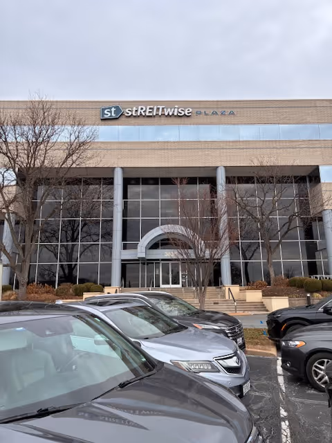 Exterior view of a brick office building entrance with cars parked in front