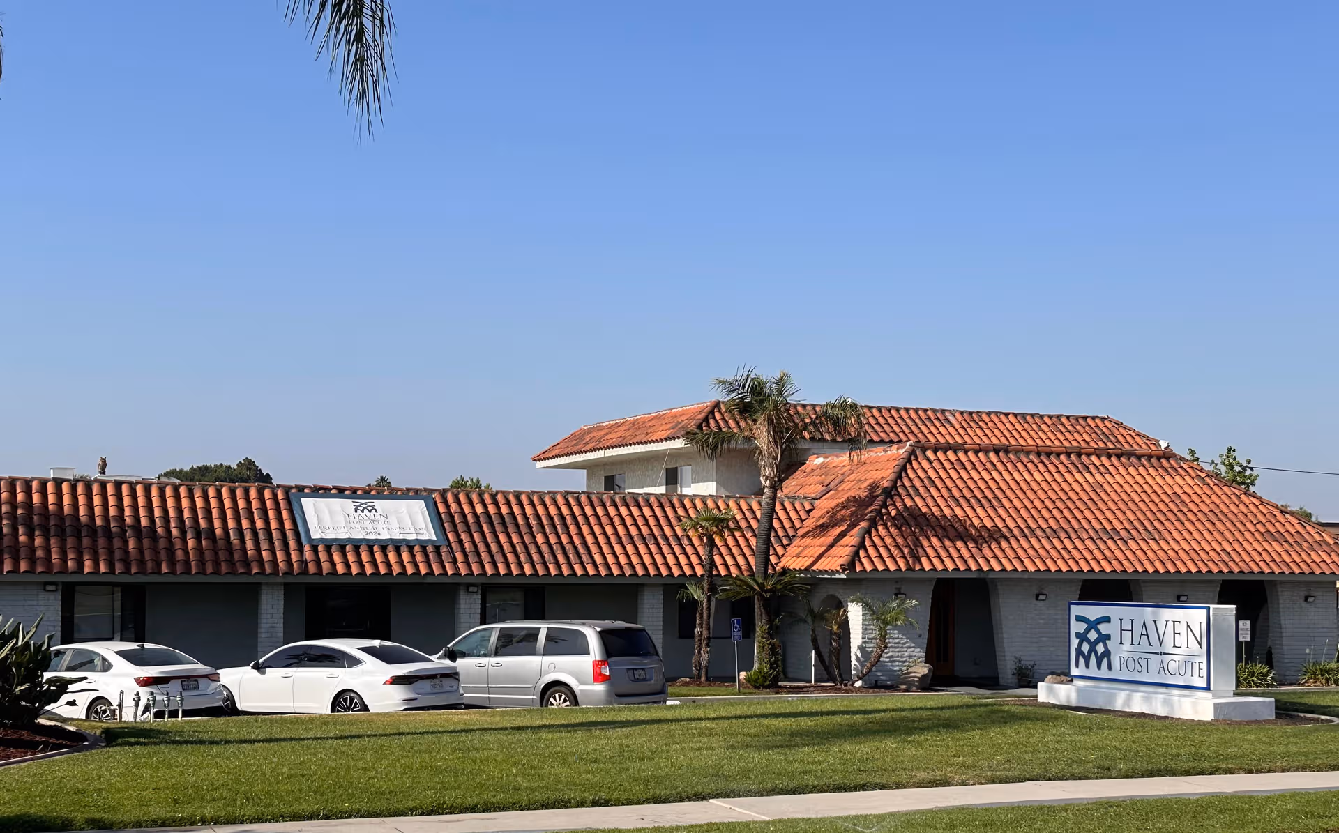 Exterior view of Haven Post Acute building with red-tiled roof and parked cars.