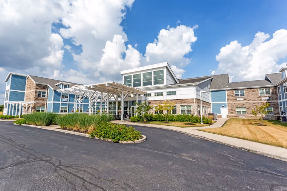 Exterior view of Clearvista Lake Health Campus building with blue sky and white clouds. The building features a combination of blue siding and brick, with large windows and a covered entrance. There is a paved driveway and landscaped greenery in front.