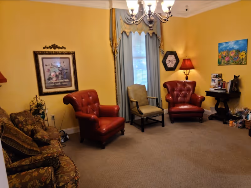 Cozy living room lounge with yellow walls, red leather chairs and blue curtains