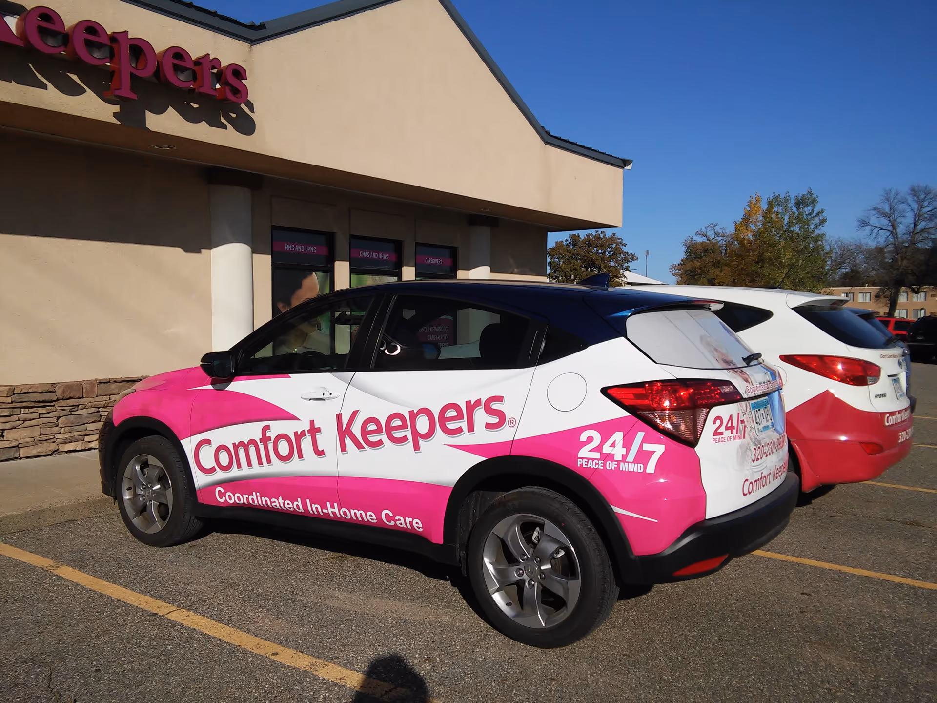 Exterior view of Comfort Keepers facility with branded pink-and-white service vehicle in parking