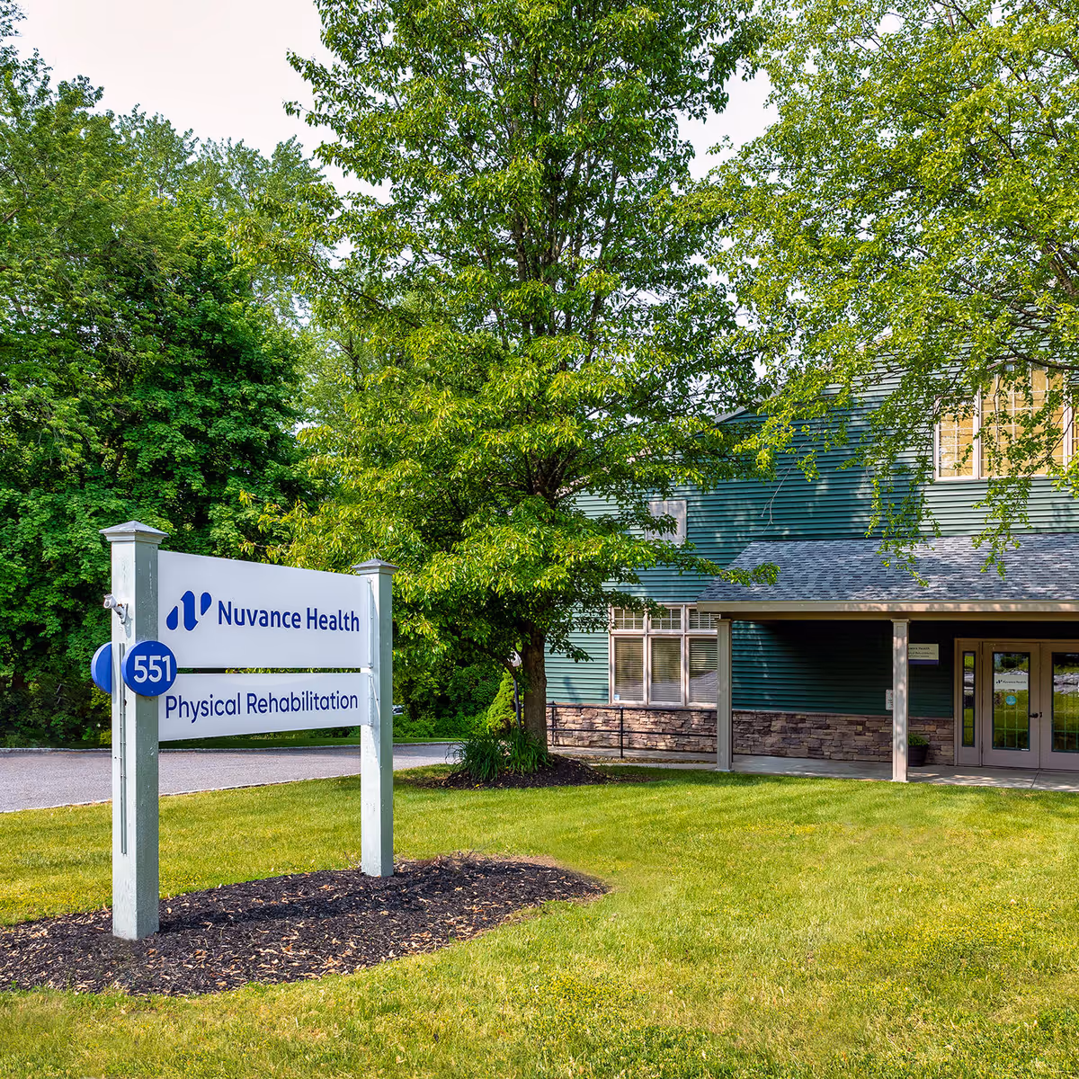 Exterior view of a green building with a Nuvance Health Physical Rehabilitation sign and trees.