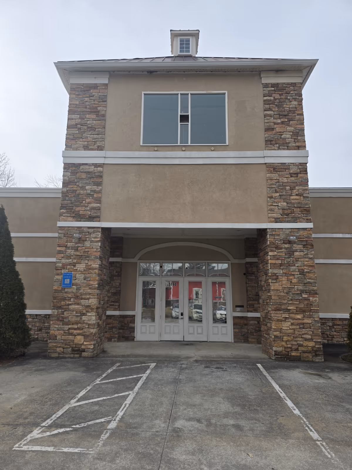 Facade of a two-story senior living facility entrance with stone columns.