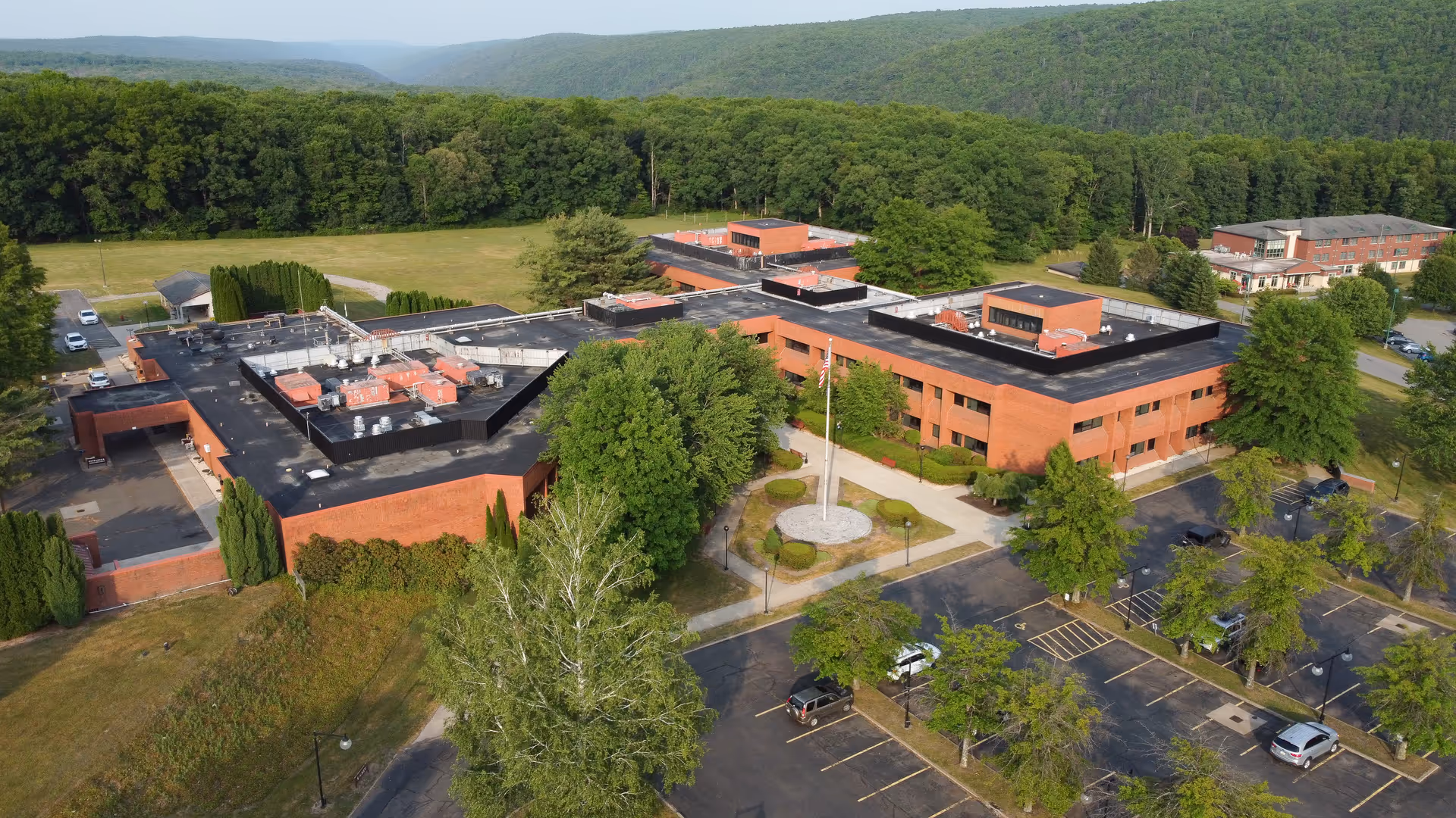Aerial view of Weatherwood Healthcare and Rehabilitation Center showing brick buildings, parking, and trees.