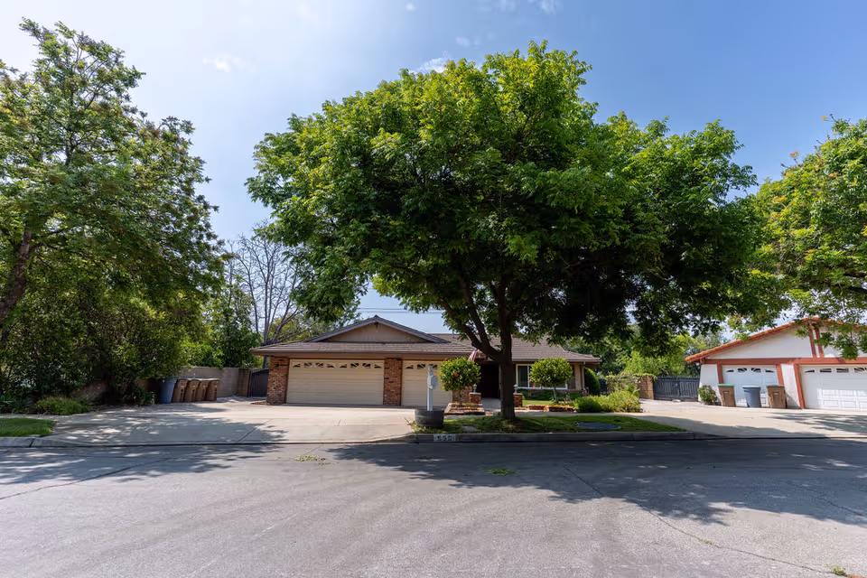 Genesis Manor V exterior showing a two-garage building and lush trees along the street.