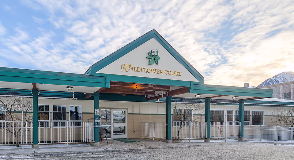 Front entrance of Wildflower Court senior living facility with a covered porte-cochere and signage on the gable.