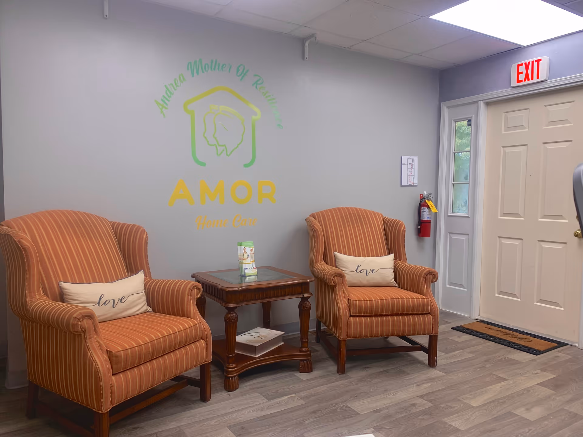 Two orange striped armchairs flank a wooden table in a lounge with AMOR logo.
