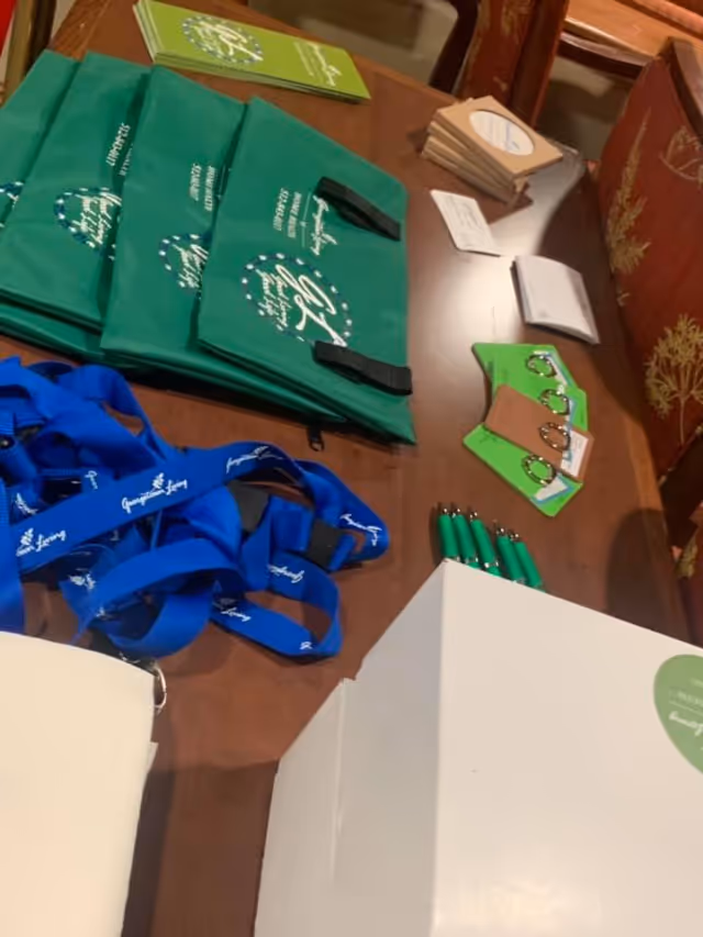 Table with Georgetown Living Home Health event bags, lanyards, and pens.