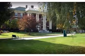 Front view of a brick building with white columns and a green well-kept lawn