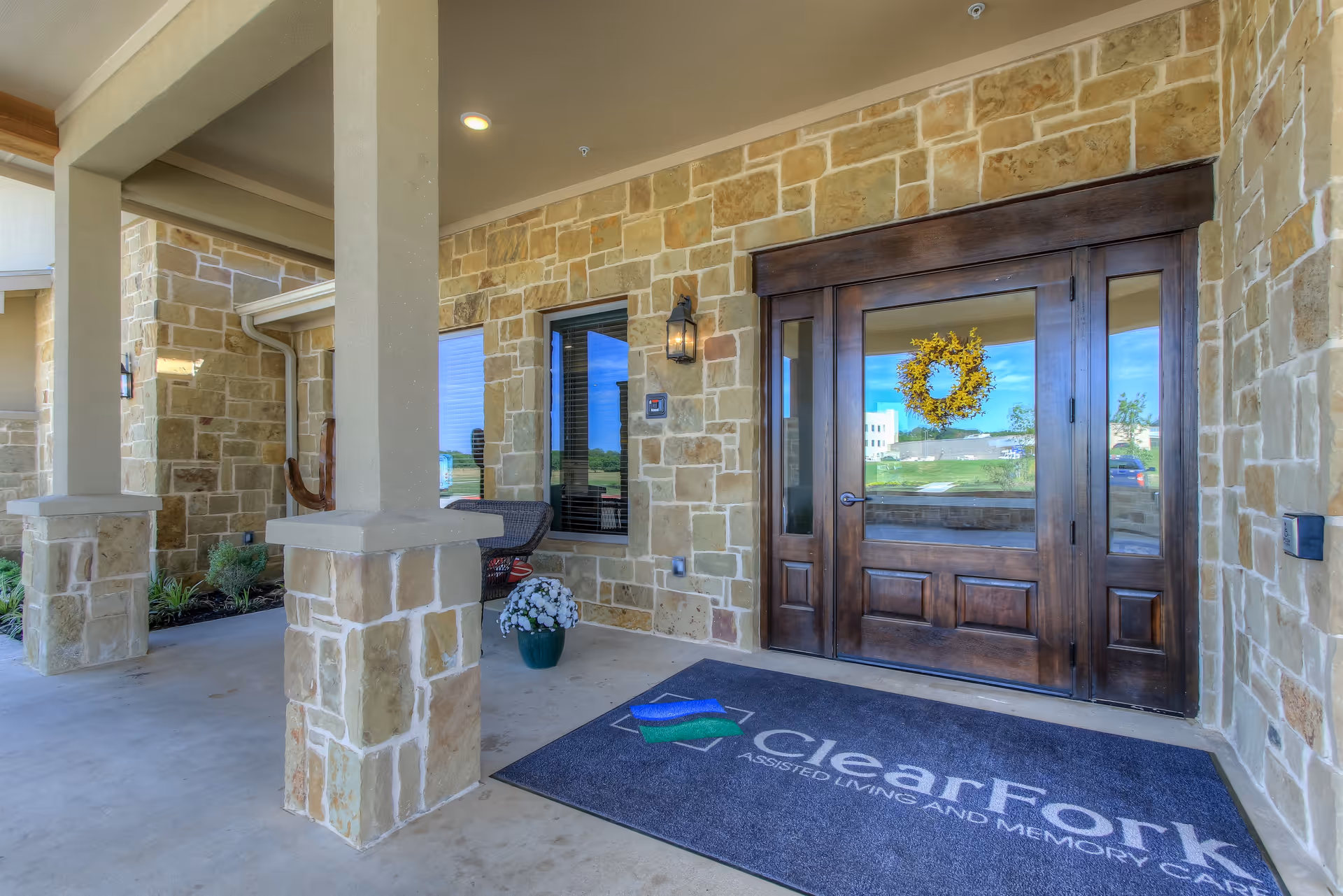 Stone-clad building entrance with large wooden doors and a ClearFork mat.
