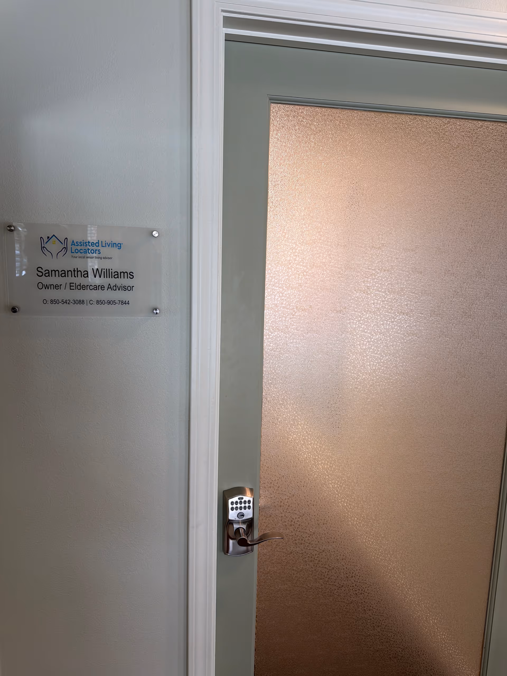 An interior door with a frosted glass panel and a nearby Assisted Living Locators plaque.