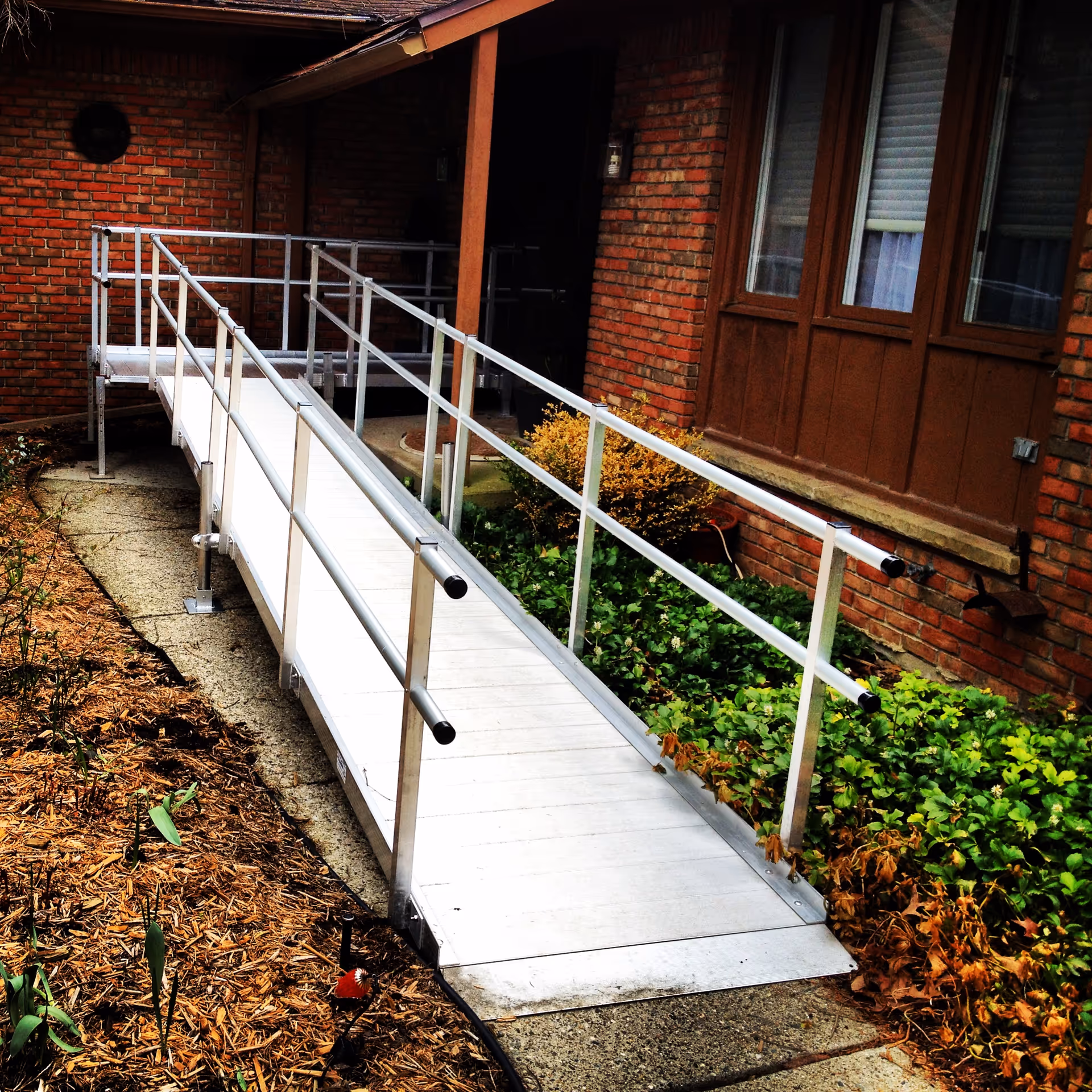 Exterior ramp with metal handrails leading to a brick building entrance.