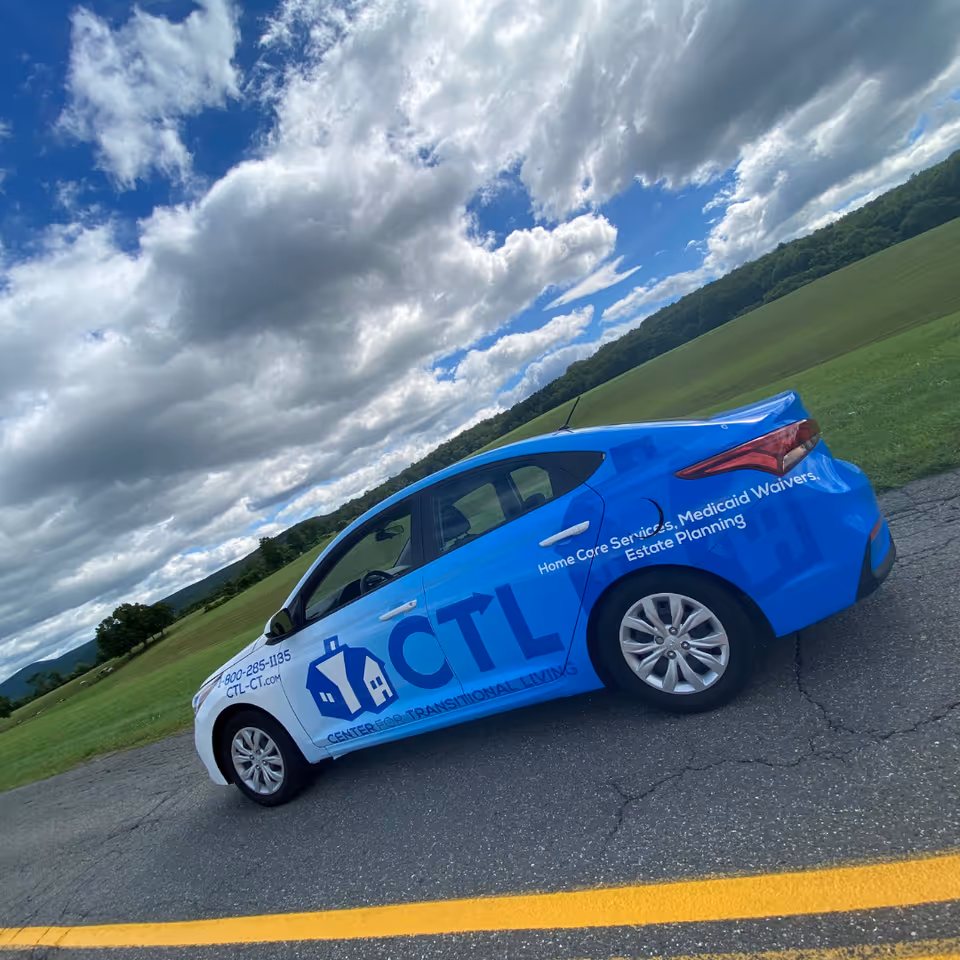 Blue promotional car for Center for Transitional Living parked on a rural road