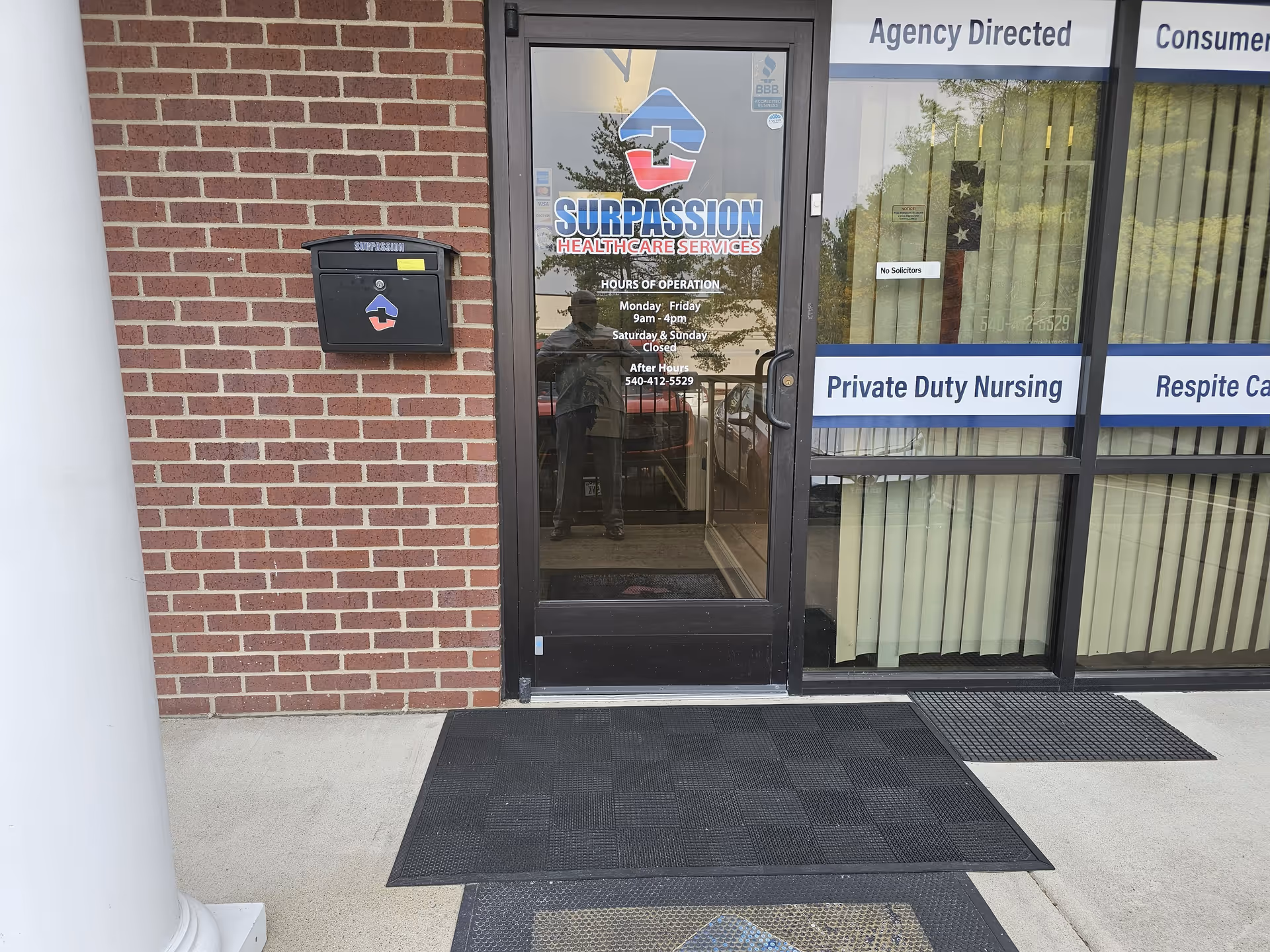 Brick building exterior with glass door, Surpassion Health Care Services logo, and window signage.