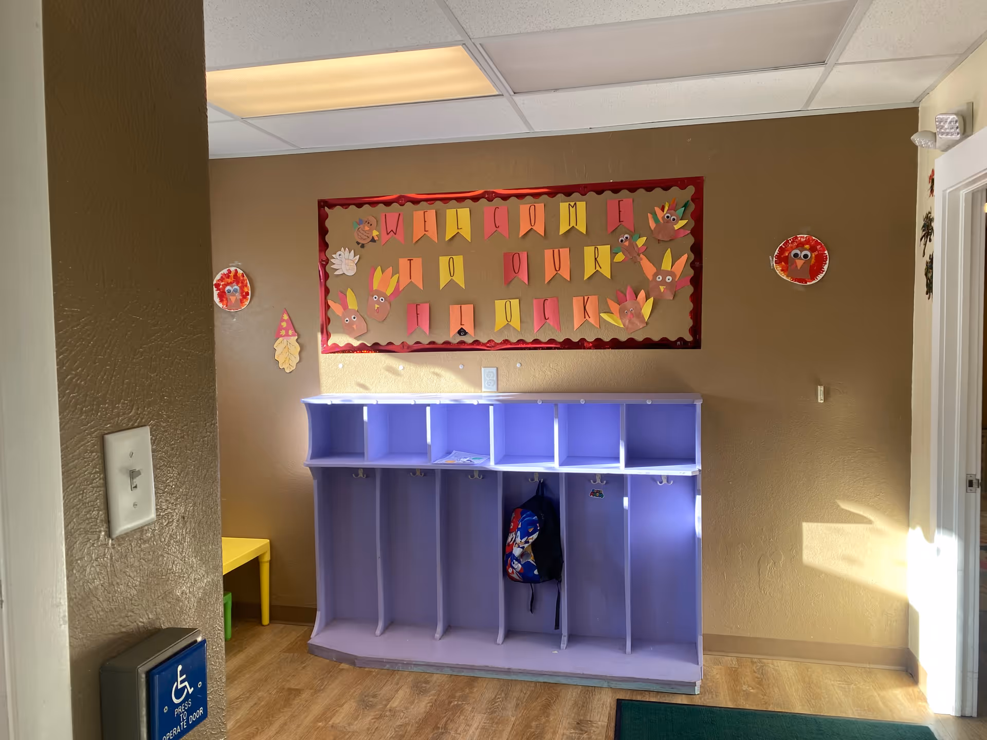 Purple cubby storage unit against beige wall with a welcome banner in hallway