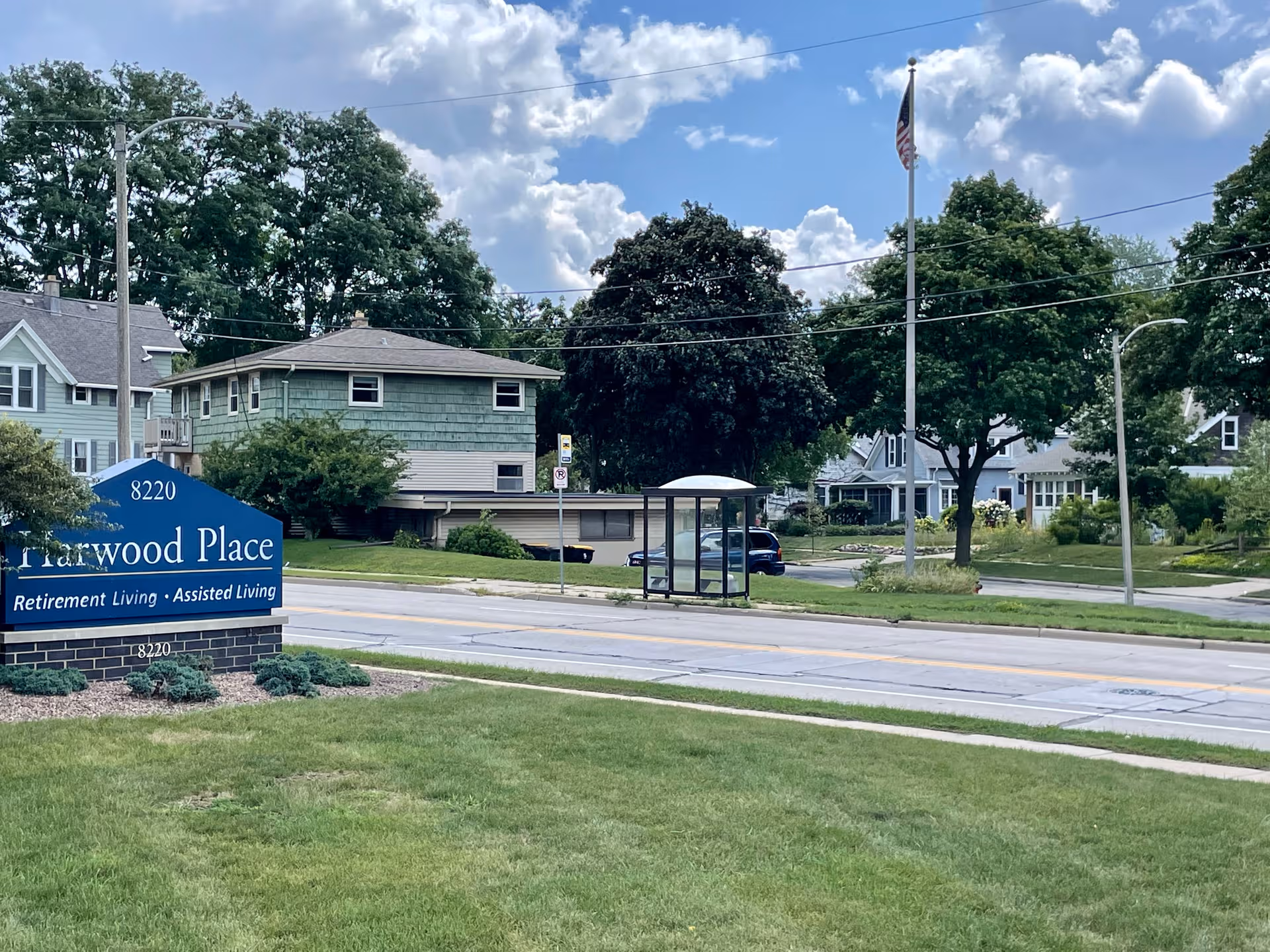 Exterior view of Harwood Place Senior Living sign and building front along a street
