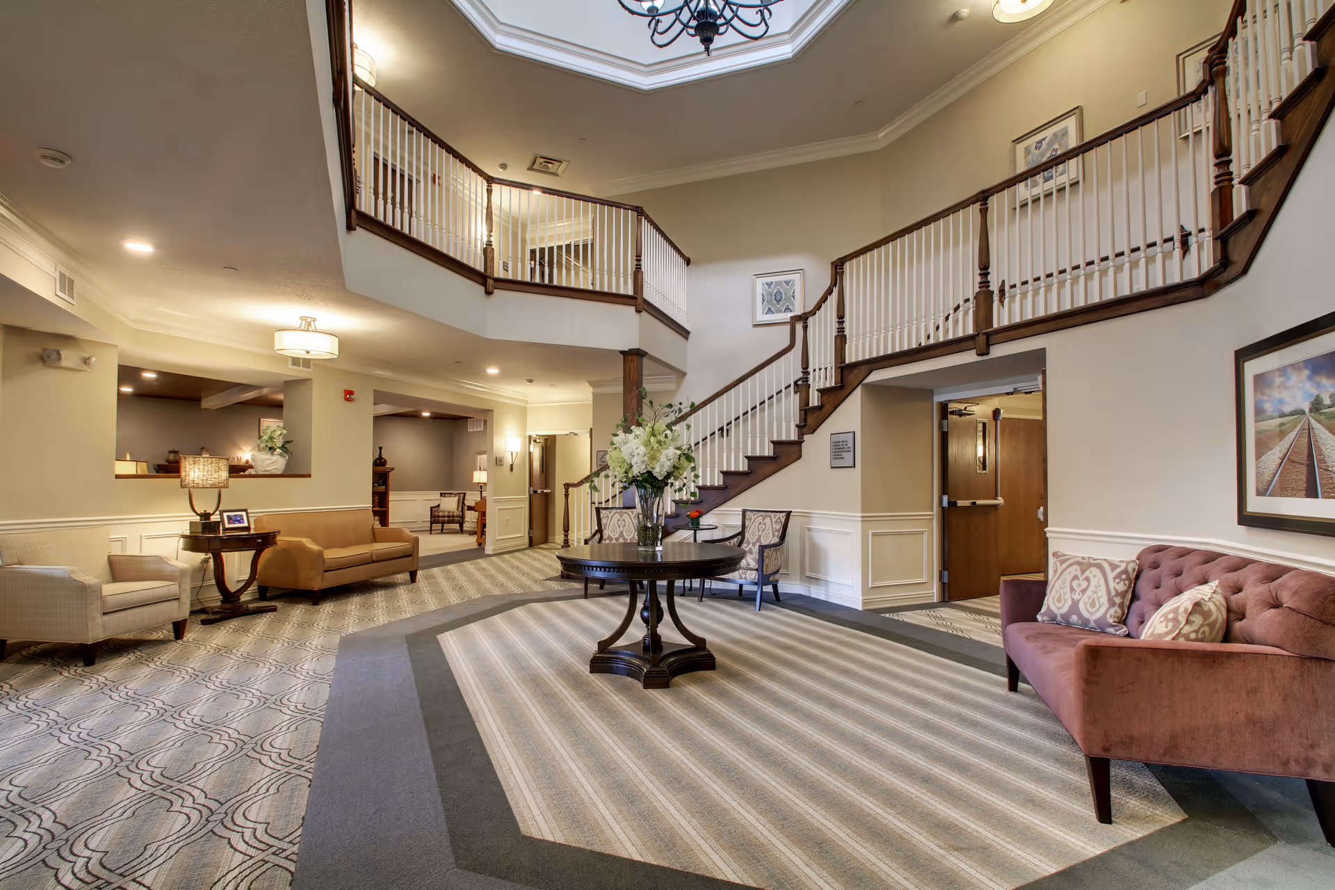 Elegant Evergreen Senior Living lobby with grand staircase, seating, and floral centerpiece.