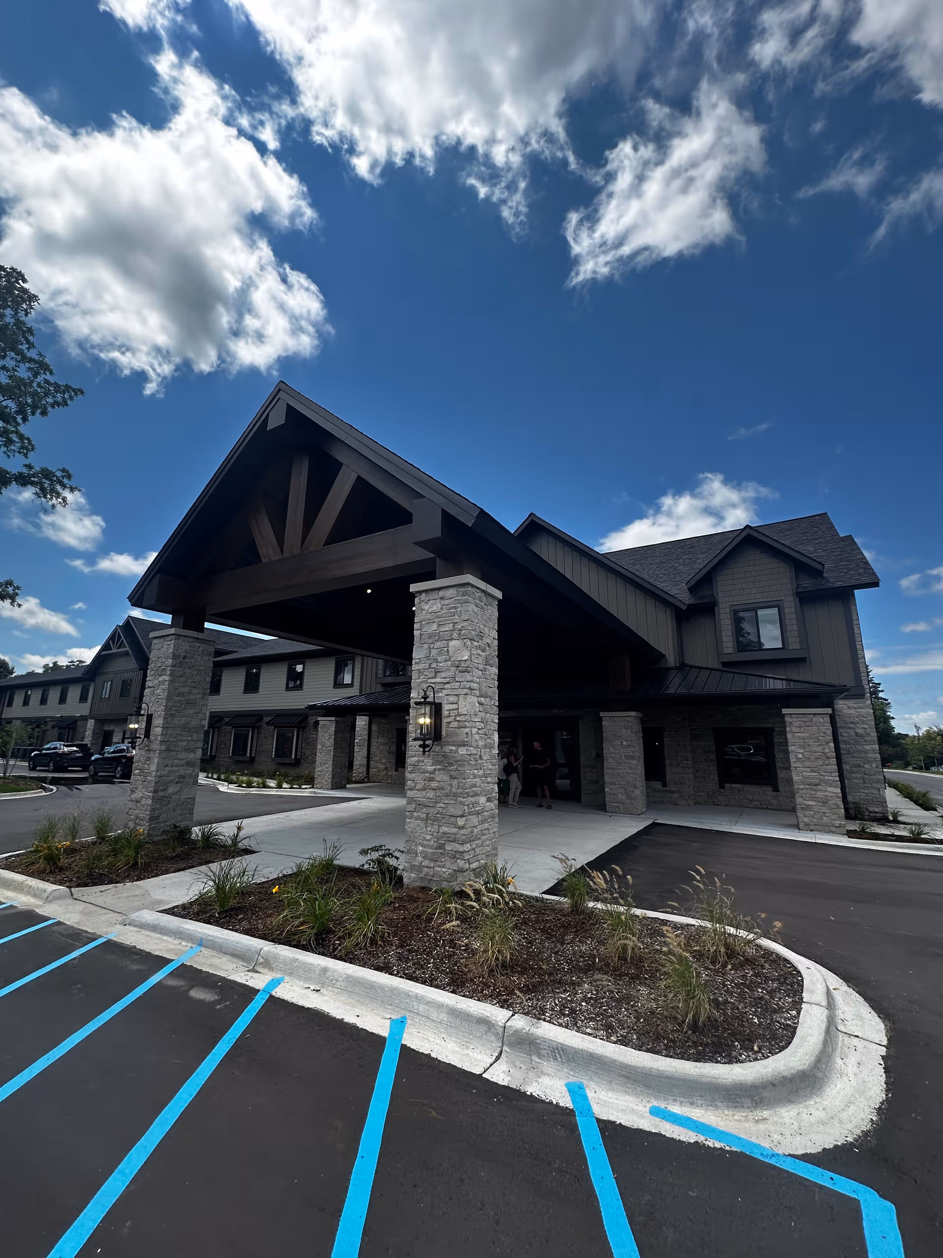 Exterior view of Grace Senior Living Rochester Hills with a covered entrance and stone pillars.