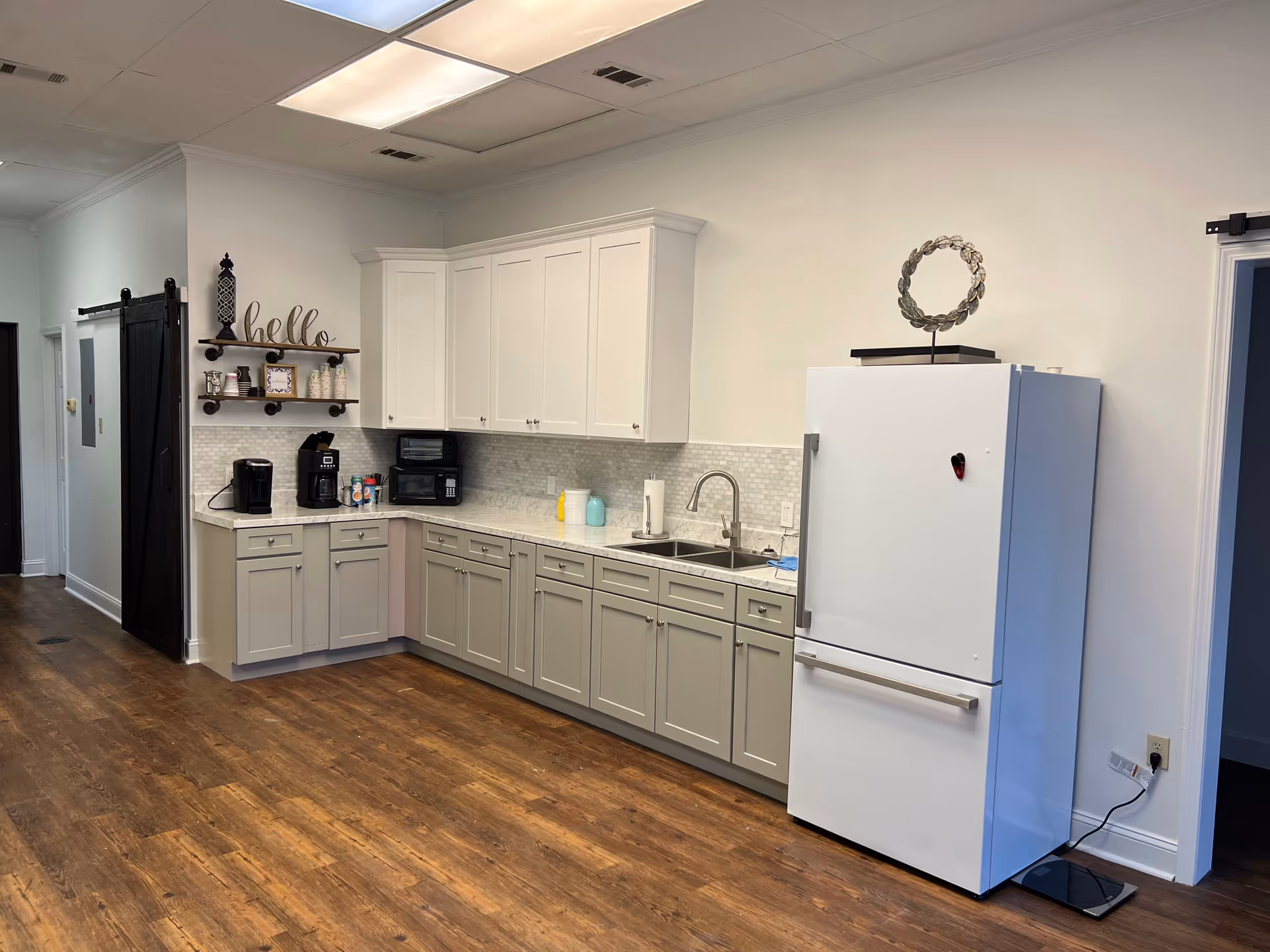Modern kitchen in a senior living facility with white cabinets, a refrigerator, and appliances.