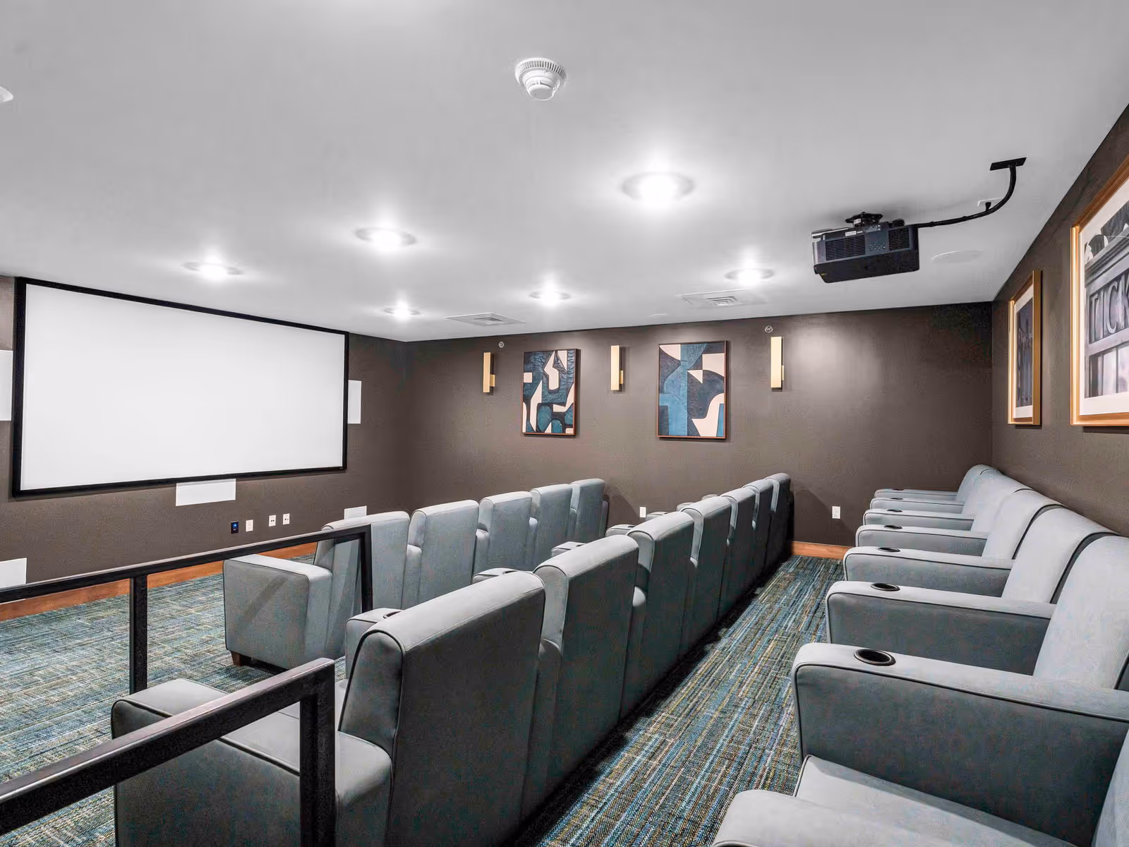 Theater room in Cedarhurst Senior Living Lincoln with projector screen and multiple gray seats.