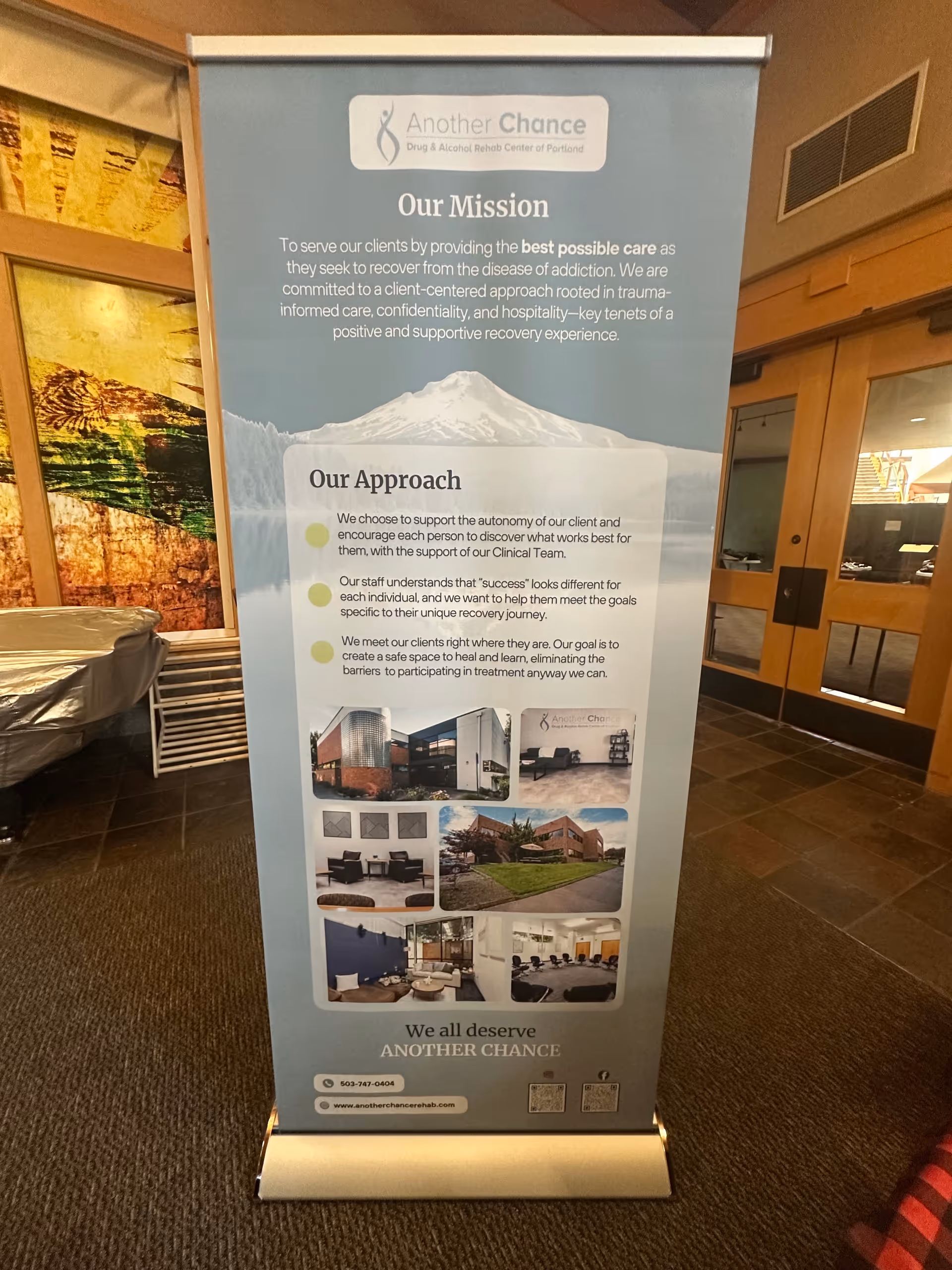 Tall blue promotional banner for Another Chance rehab center stands in a modern indoor lobby.