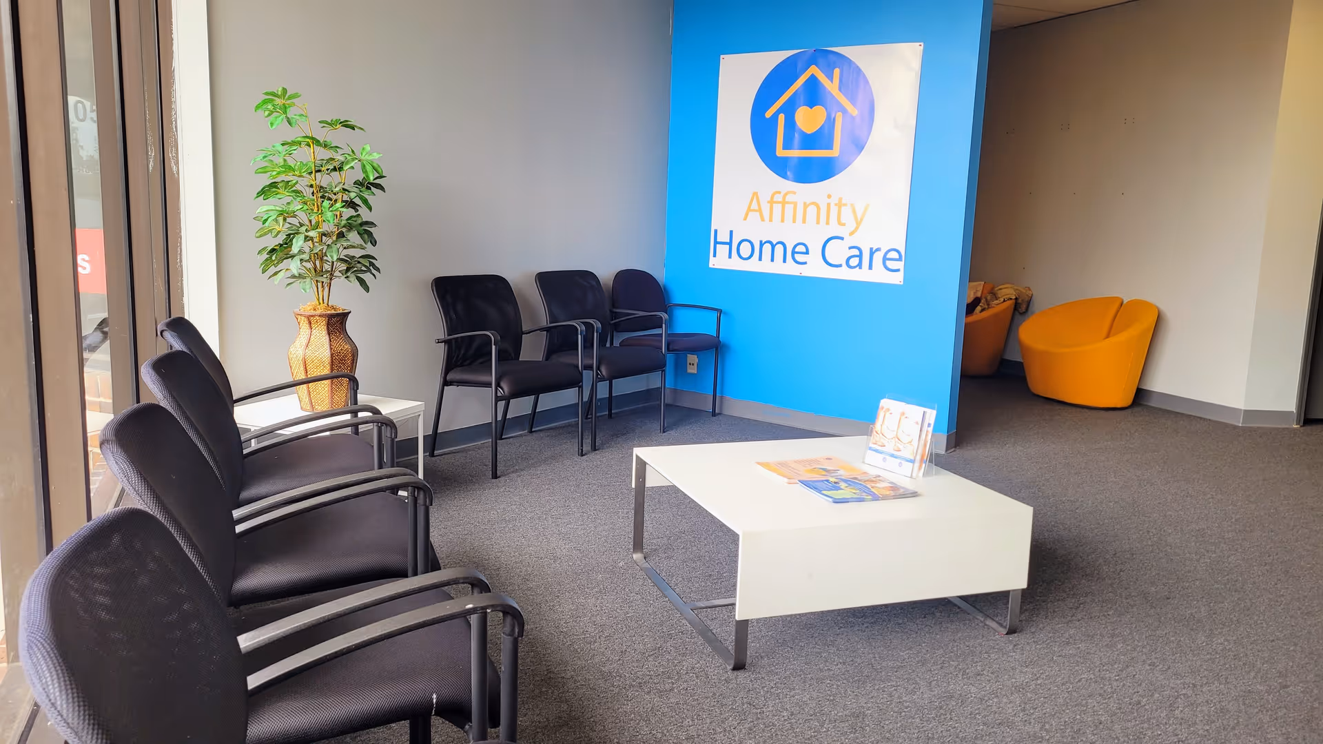 Lobby with black chairs along wall, blue Affinity Home Care sign, and white coffee table.