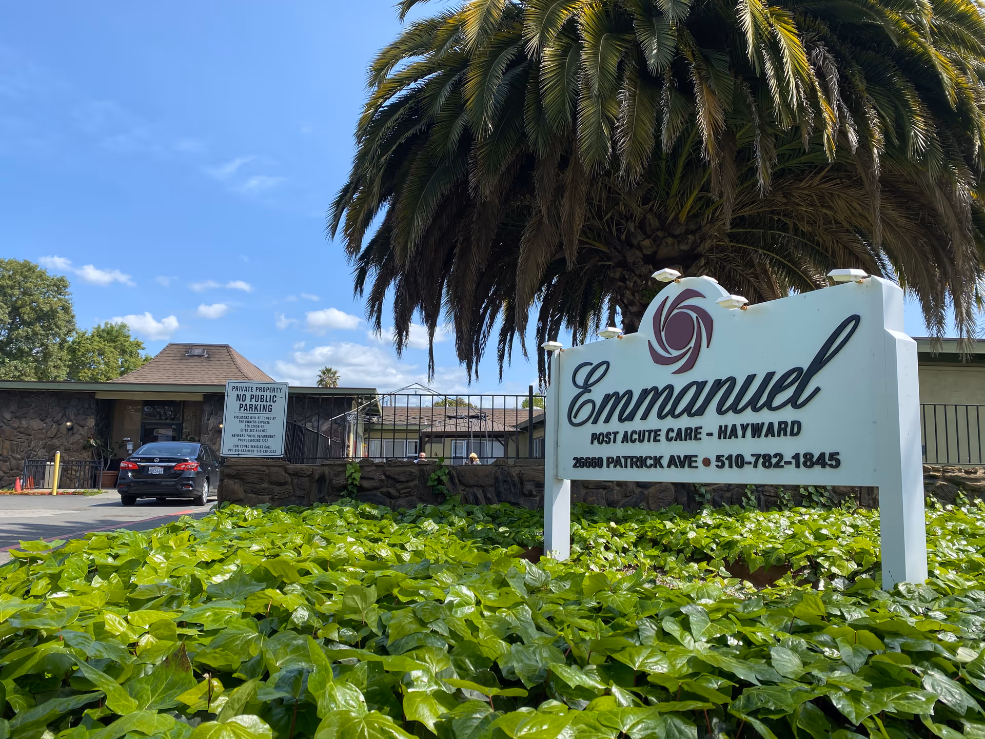 Front exterior of Emmanuel Post Acute Care sign with palm tree and greenery