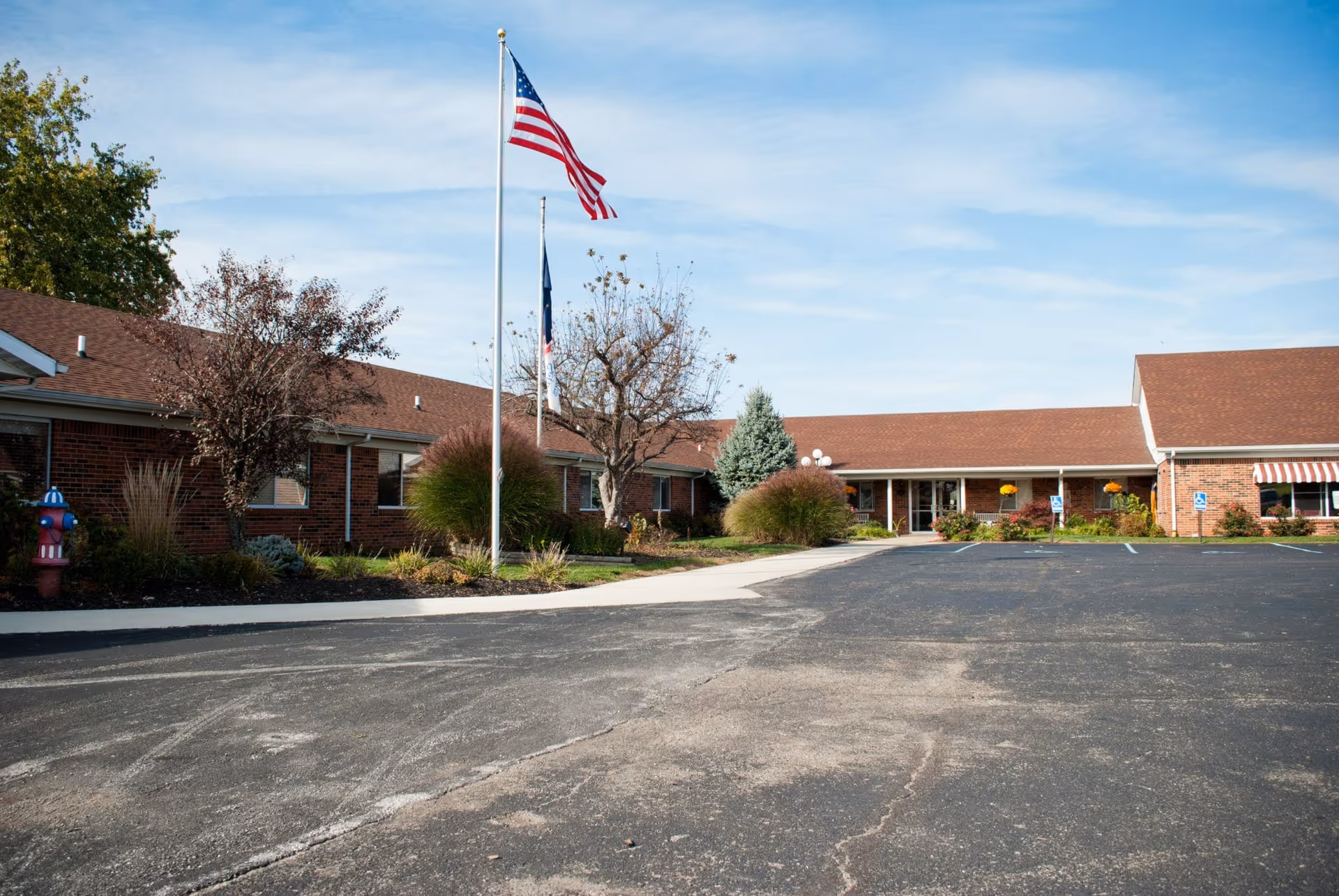 Front exterior of a single-story brick healthcare building with flagpoles, landscaping, and an empty parking lot.