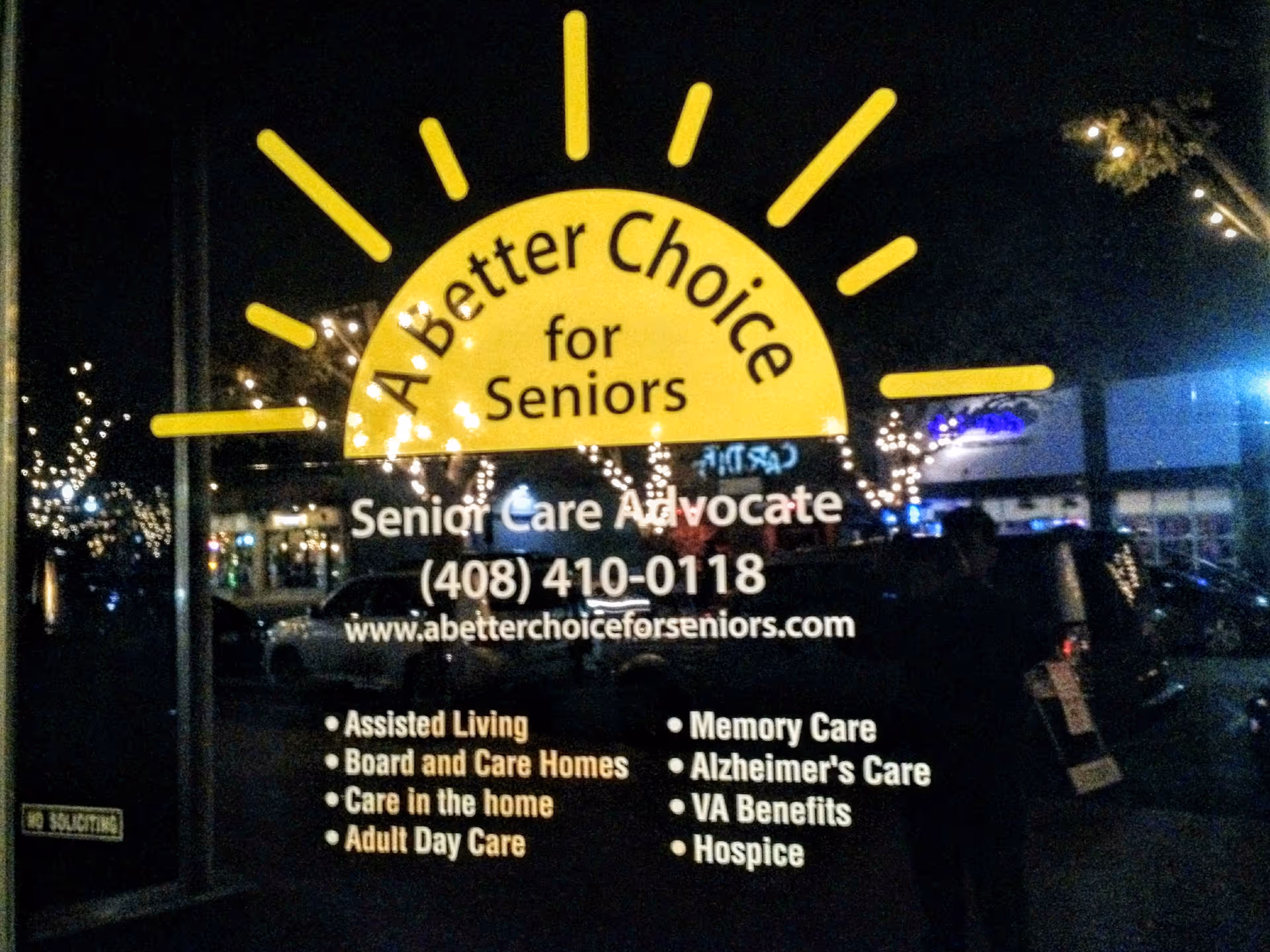 Nighttime storefront window with a yellow sun logo advertising senior care services.