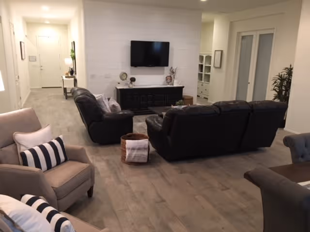 Bright living room with leather sofas, a wall mounted TV, and a dark console.
