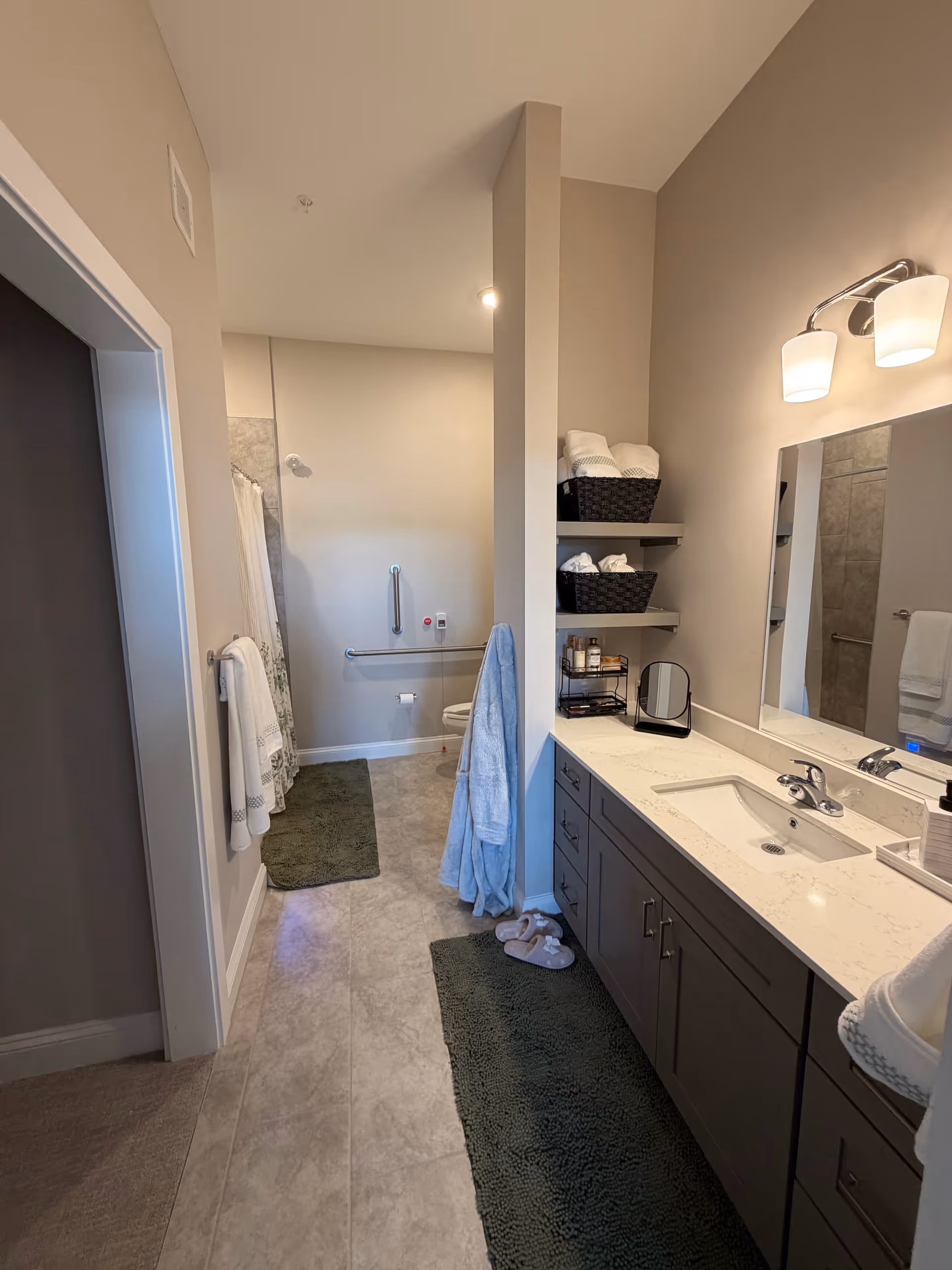 Modern bathroom with double-sink vanity, towels, shelves, and a walk-in shower.
