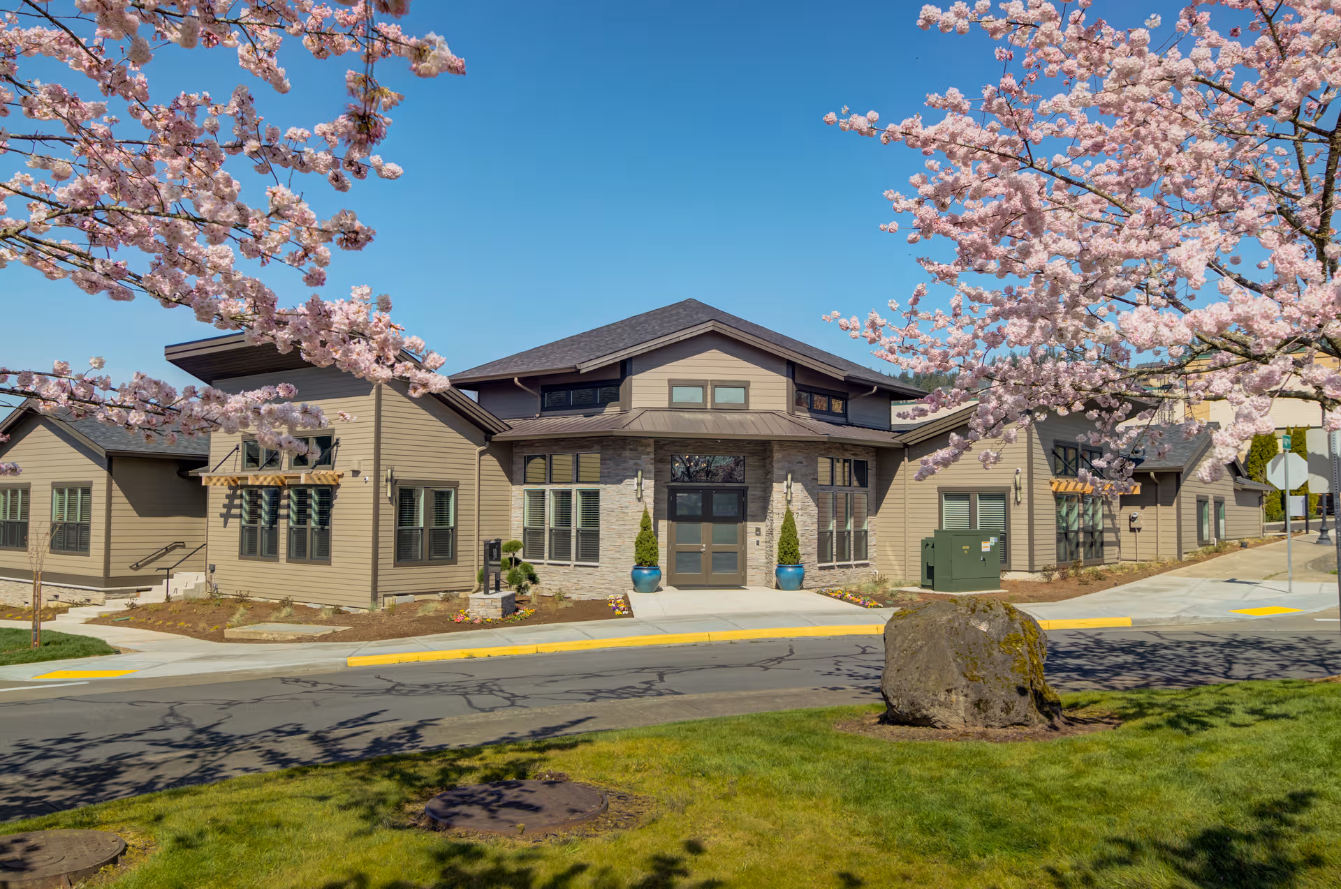 Miracle Heights exterior front view with blooming pink blossoms and a blue sky.