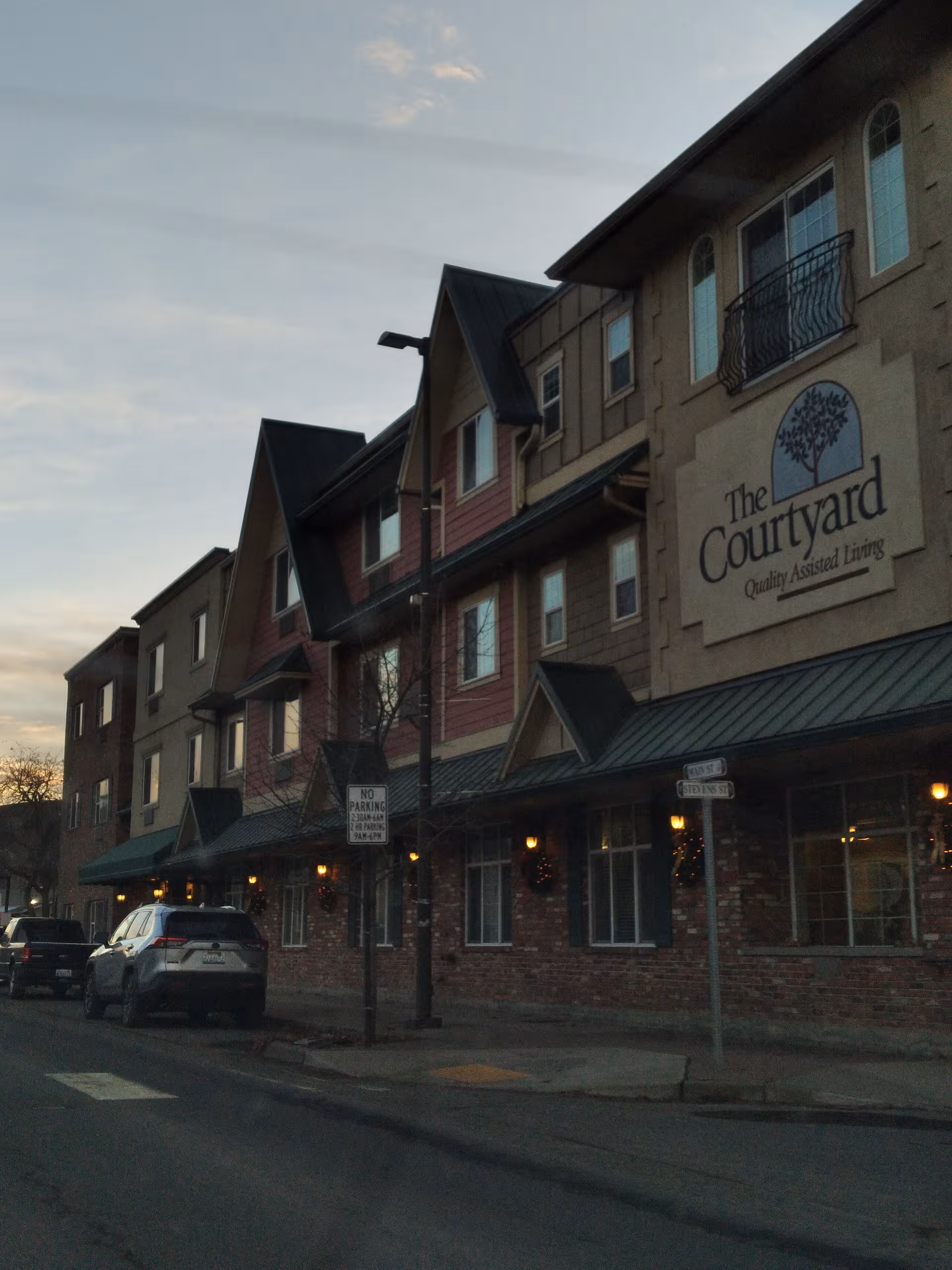 Exterior view of The Courtyard Assisted Living facility with a sign and parked cars.