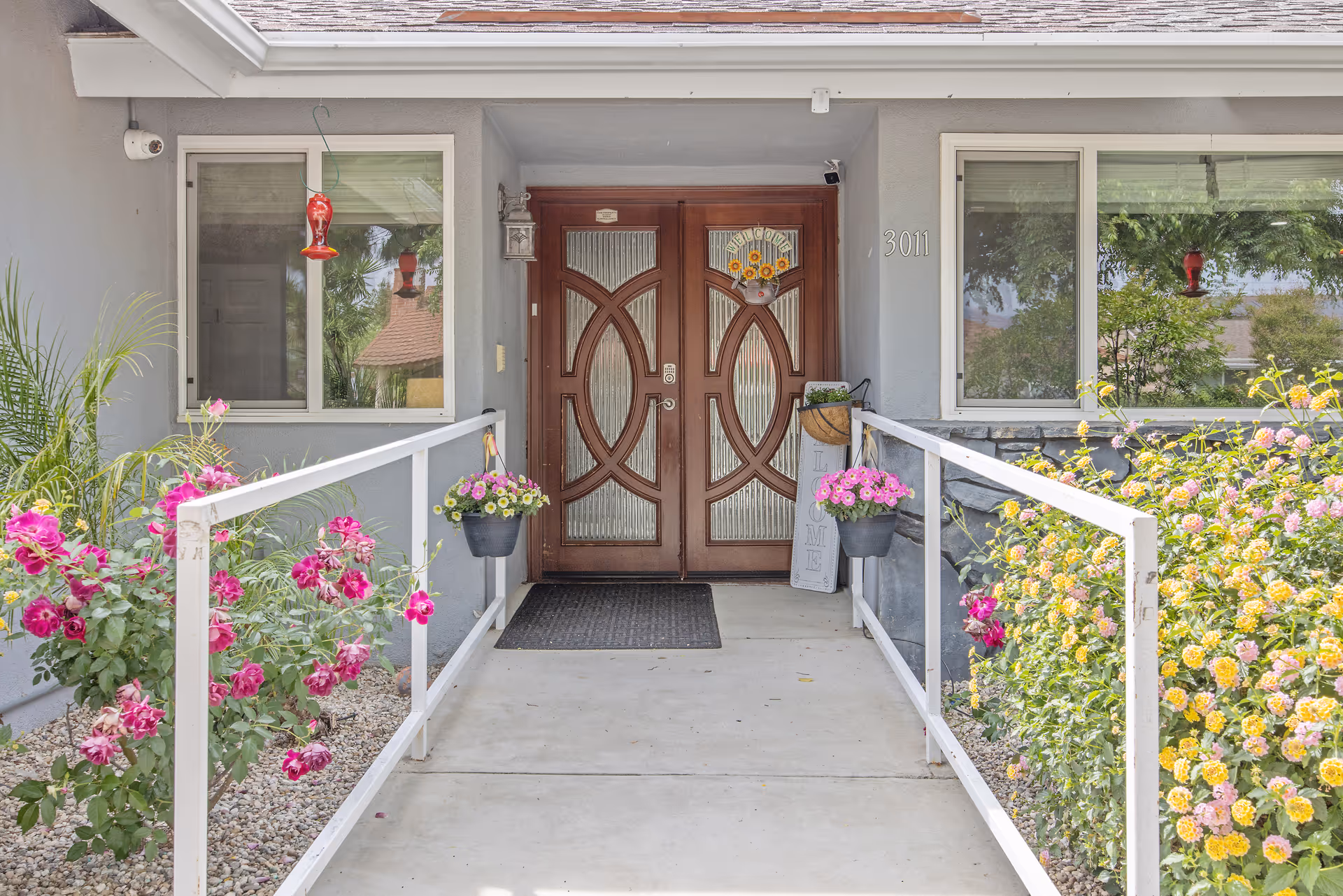 Front entrance of Regal Residence senior living facility with double wooden doors and flower planters.