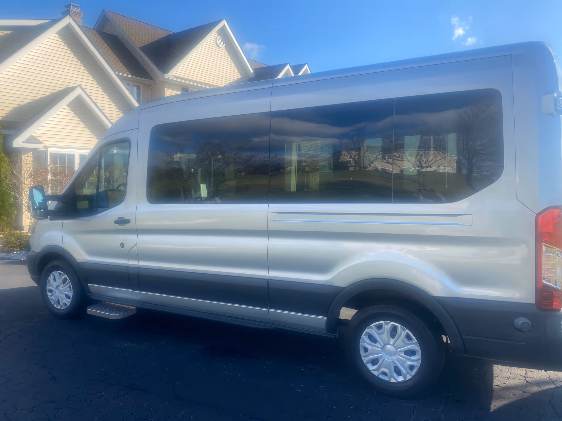White passenger van parked in front of beige residential building.